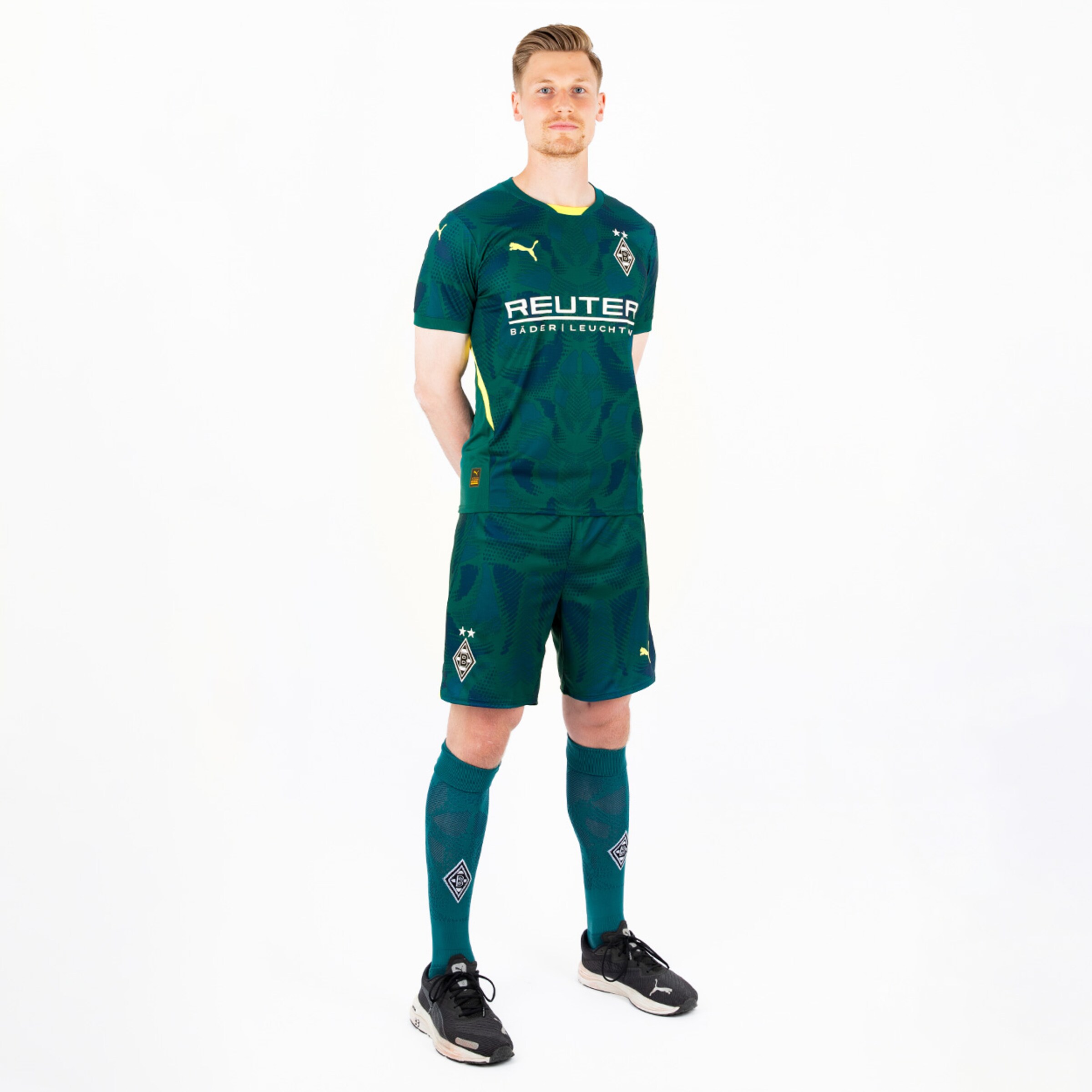 Spieler in grünem Trikot mit kurzen Ärmeln steht in gerader Haltung.