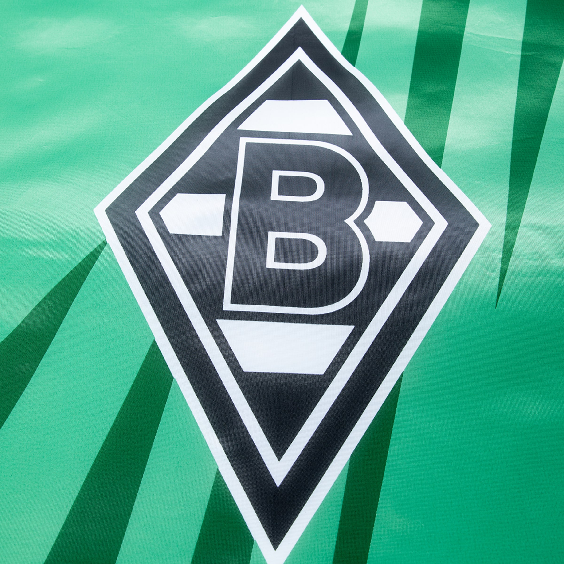 Logo von Borussia Mönchengladbach auf grünem Hintergrund mit dunkelgrünen diagonalen Streifen.
