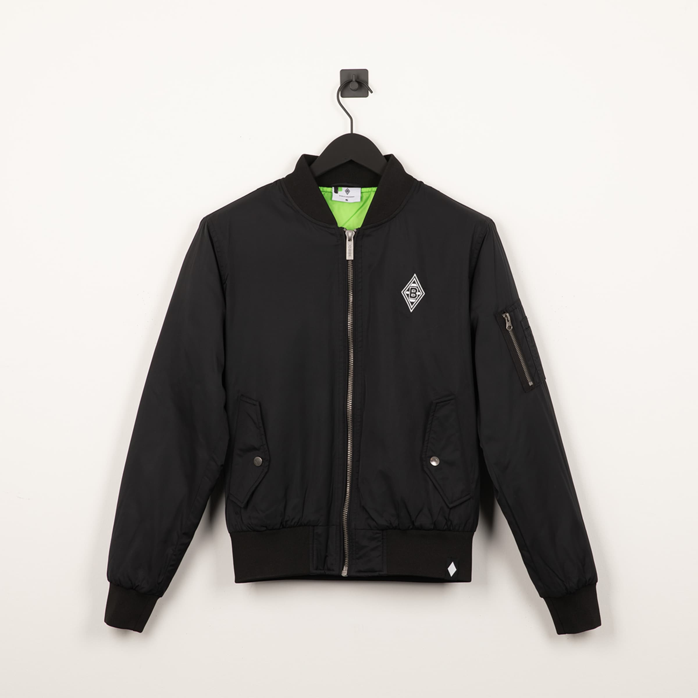Black bomber jacket with neon green lining and a white diamond logo on the chest, hanging against a white background.