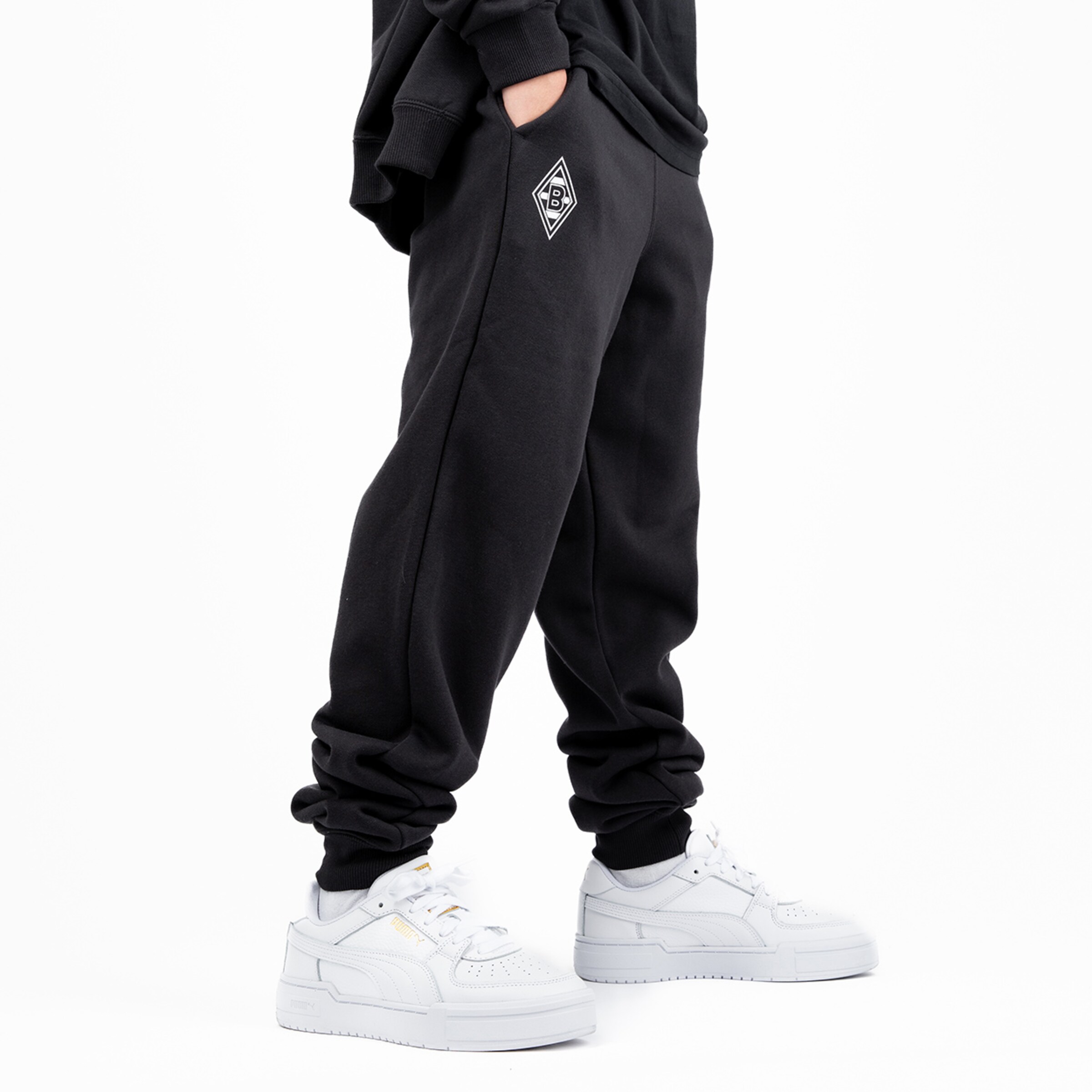 Schwarze Jogginghose mit Logo von Borussia Mönchengladbach kombiniert mit weißen Sneakern.