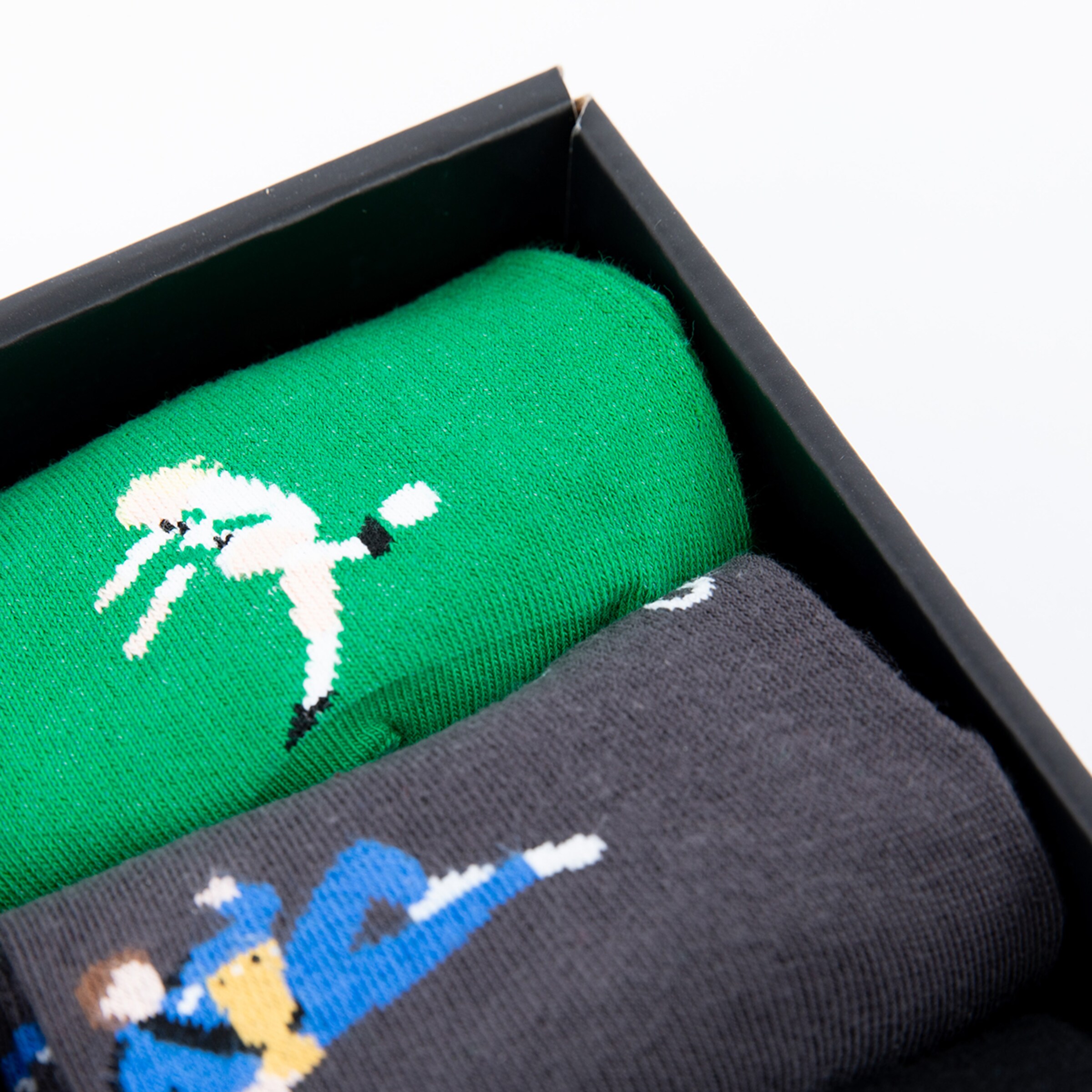 Socks in a box one featuring a green artistic player design the other in black with a player design.