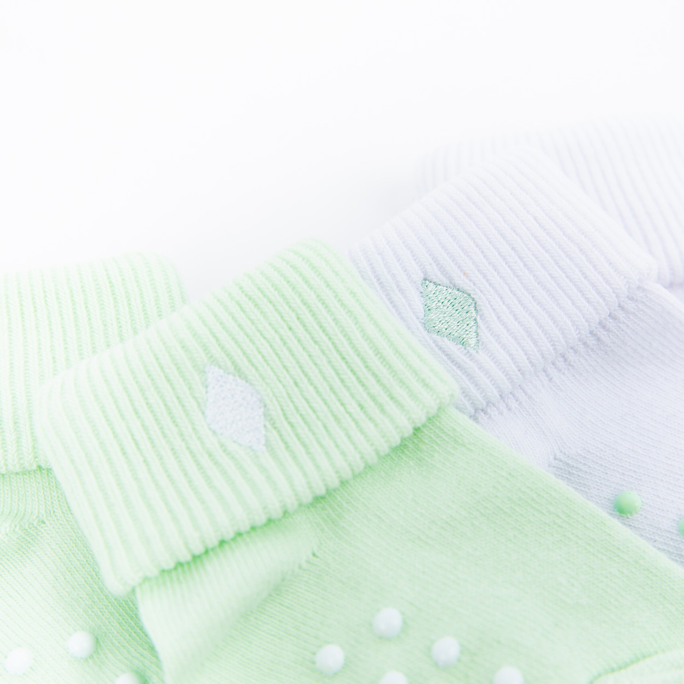 Zwei Paar Socken in verschiedenen Farben eine in mintgrün und die andere in weiß beide mit glänzenden Details.