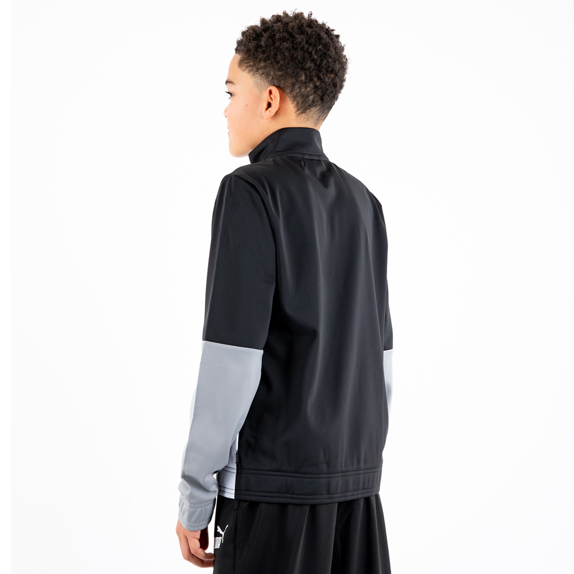 Boy wearing a black sports jacket with gray sleeves viewed from the back.