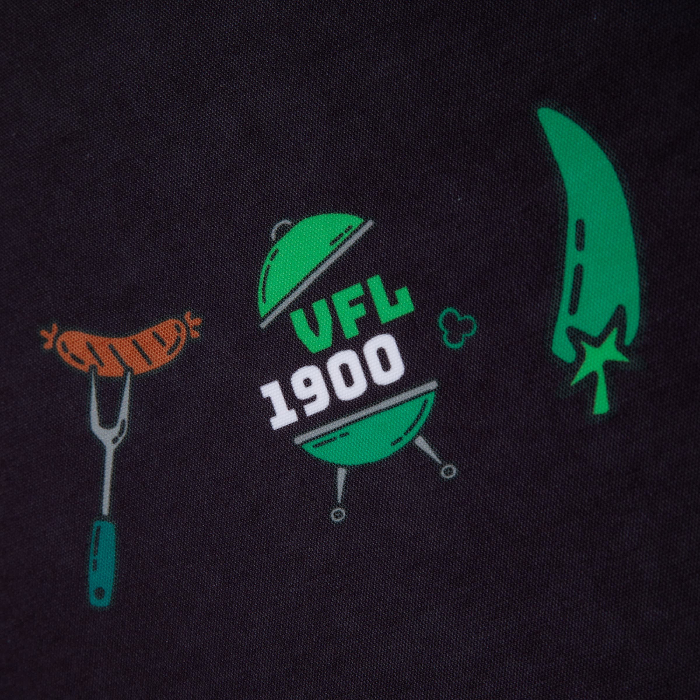 Grüner Kugelgrill mit „VFL 1900“-Schriftzug, flankiert von einer Grillwurst auf einer Gabel und einer grünen Chilischote auf schwarzem Stoff.
