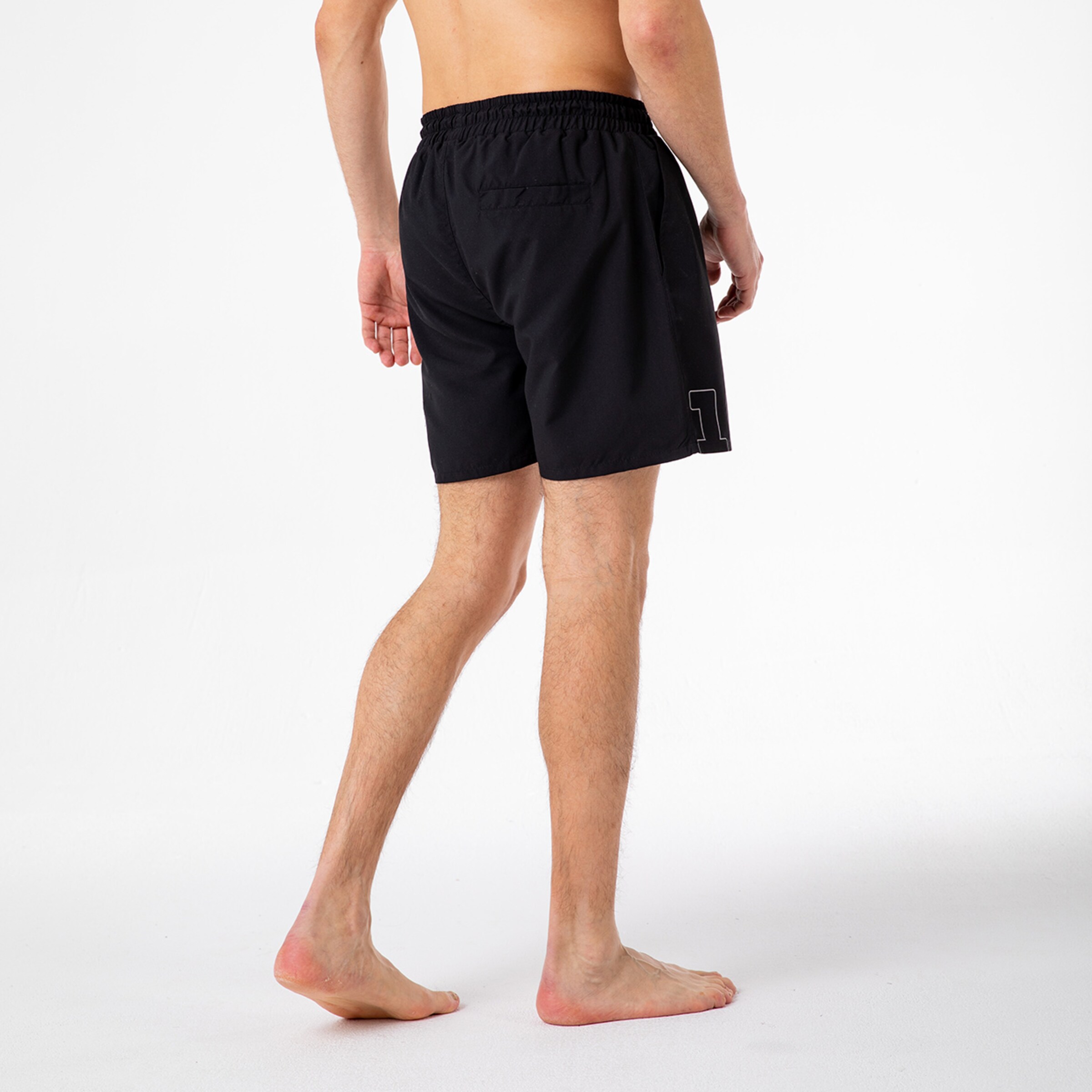 Kurze schwarze Badehose mit elastischem Bund und gestickter Zahl auf der Seite.
