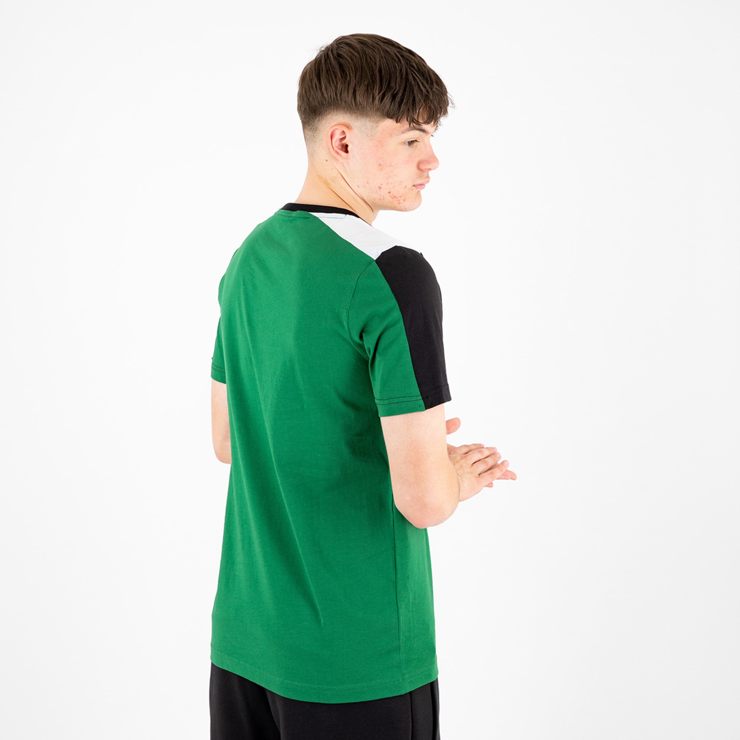 Young man stands with back to the camera wearing a green t-shirt with black and white sleeves.