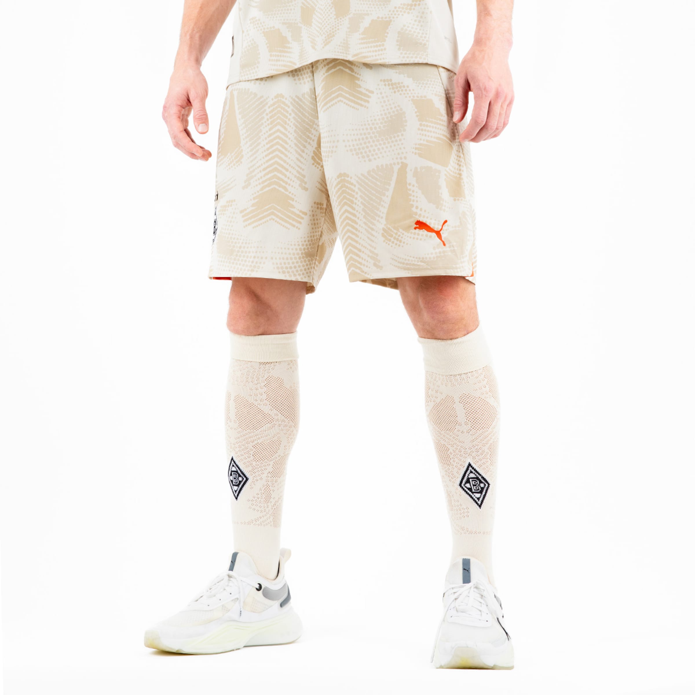 Person in beiger Sportkleidung und weißen Sneakers.