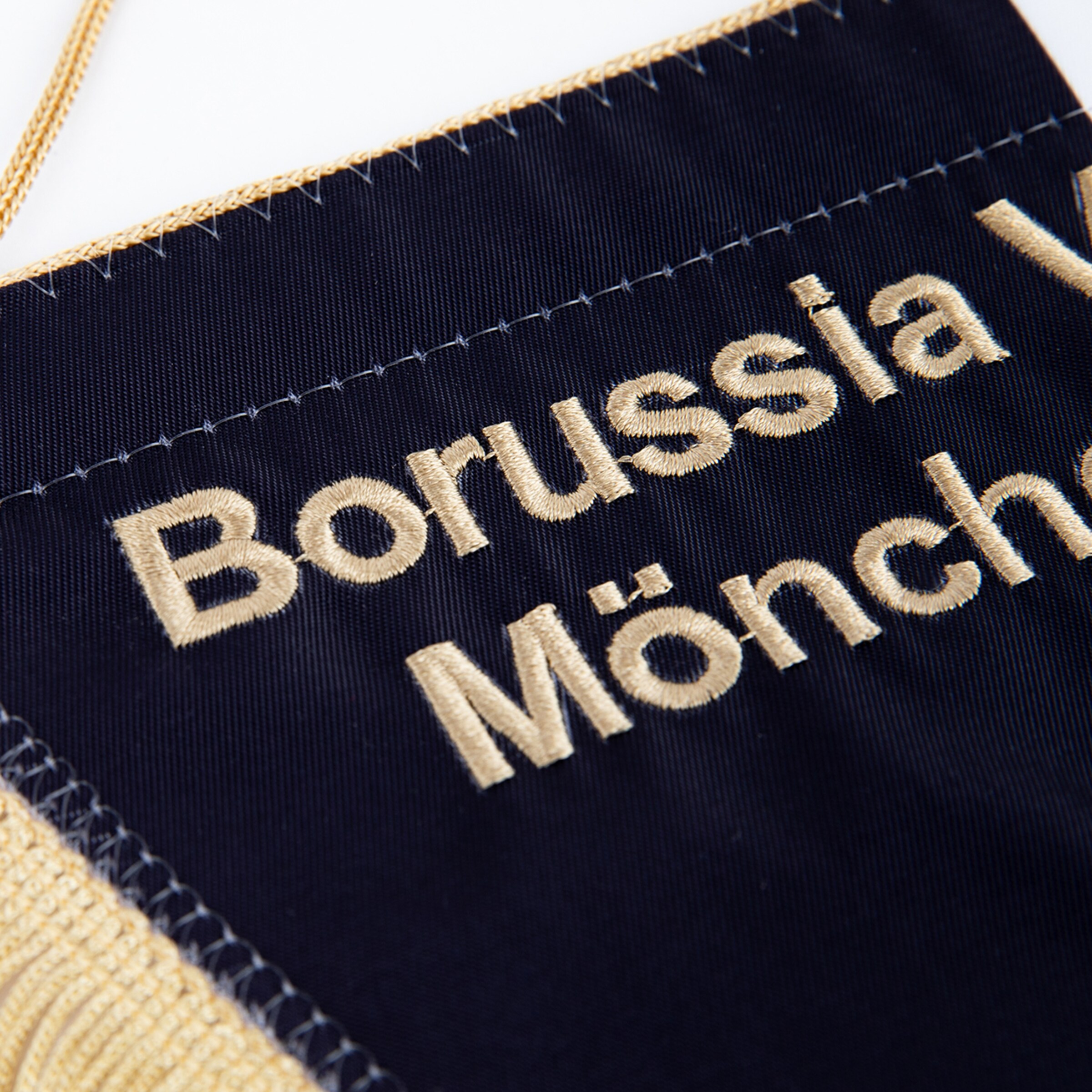 Wappen von Borussia Mönchengladbach auf einem Stoffbanner mit goldener Schrift.
