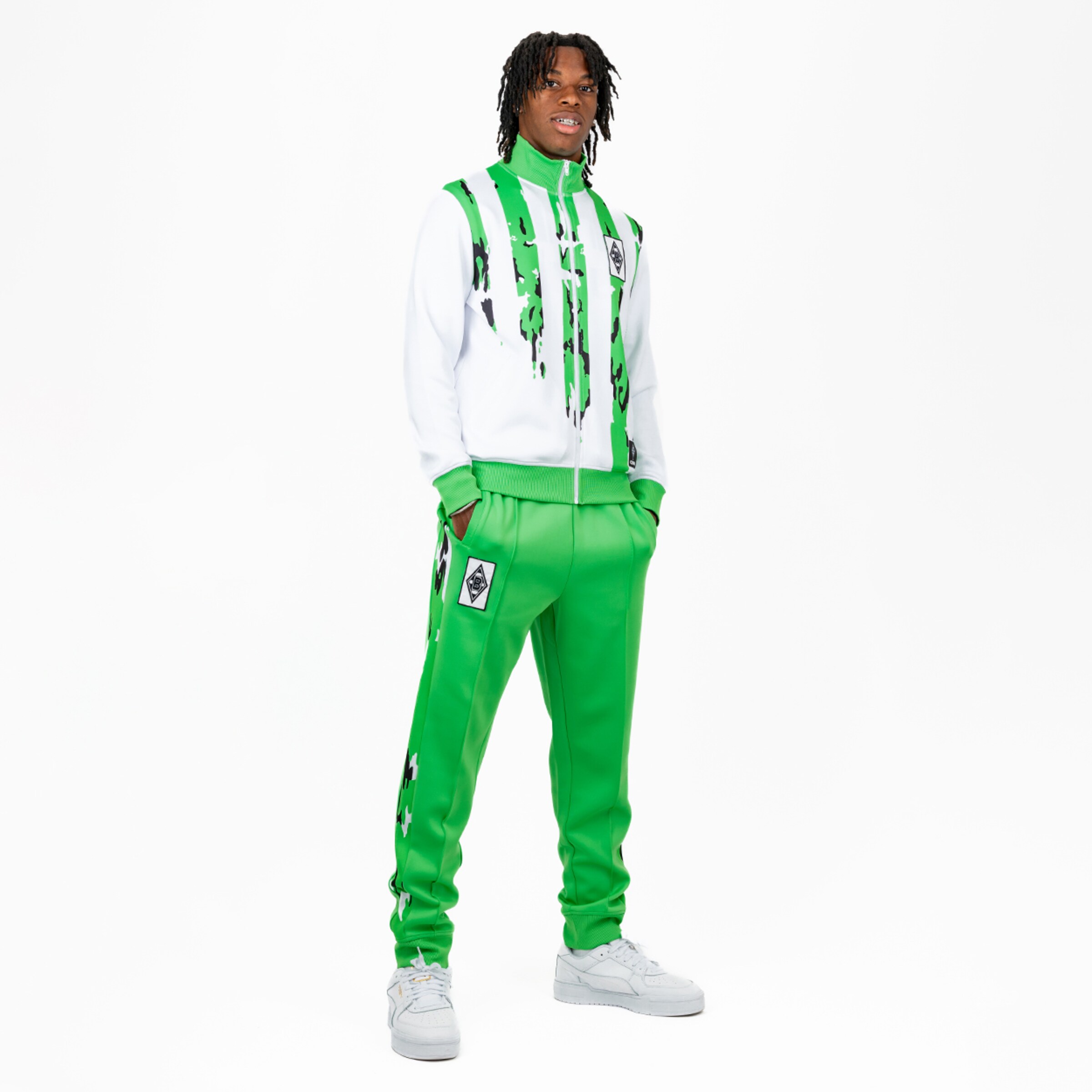 Tracksuit in white and green with graffiti pattern model standing in neutral pose.