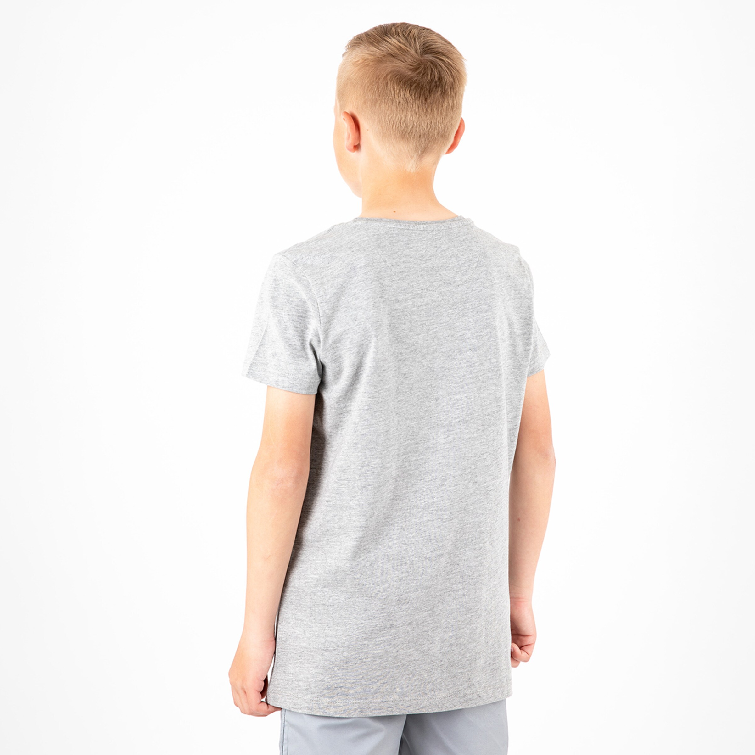 Junge mit grauem T-Shirt von hinten fotografiert steht in neutraler Pose.