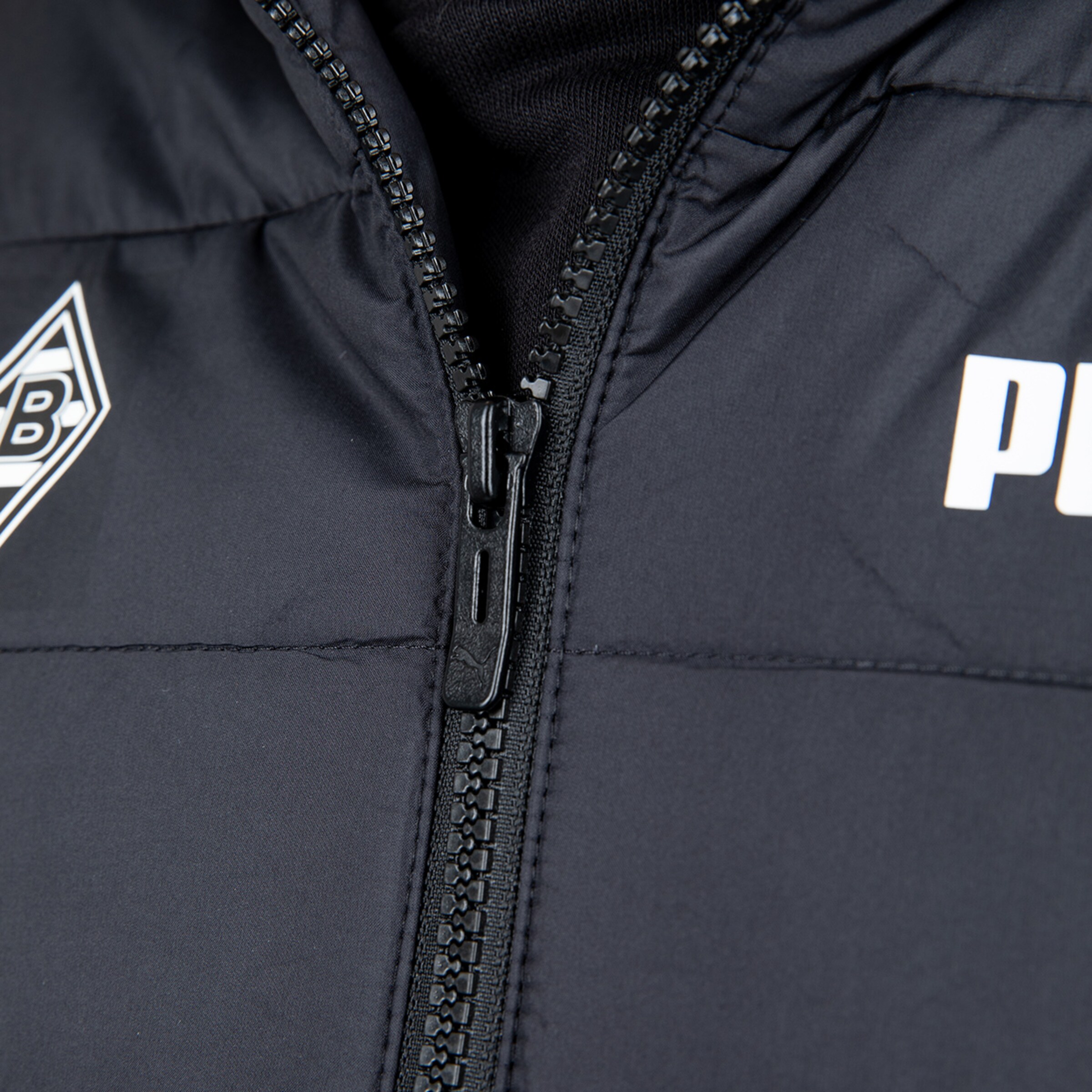 Close-up of the zipper on a black jacket featuring Borussia Mönchengladbach emblem and Puma logo.