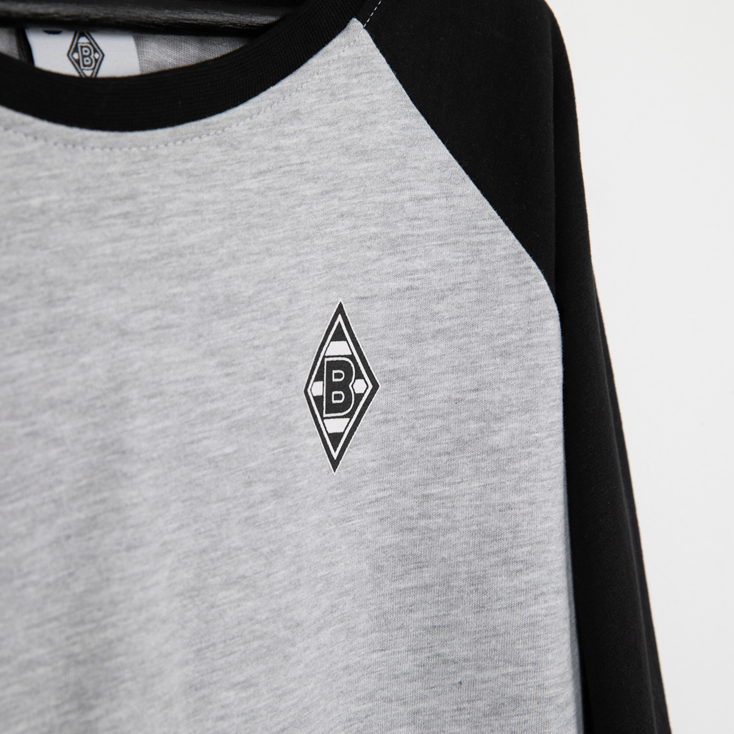 Grau-schwarzes Oberteil mit Borussia Mönchengladbach Logo.