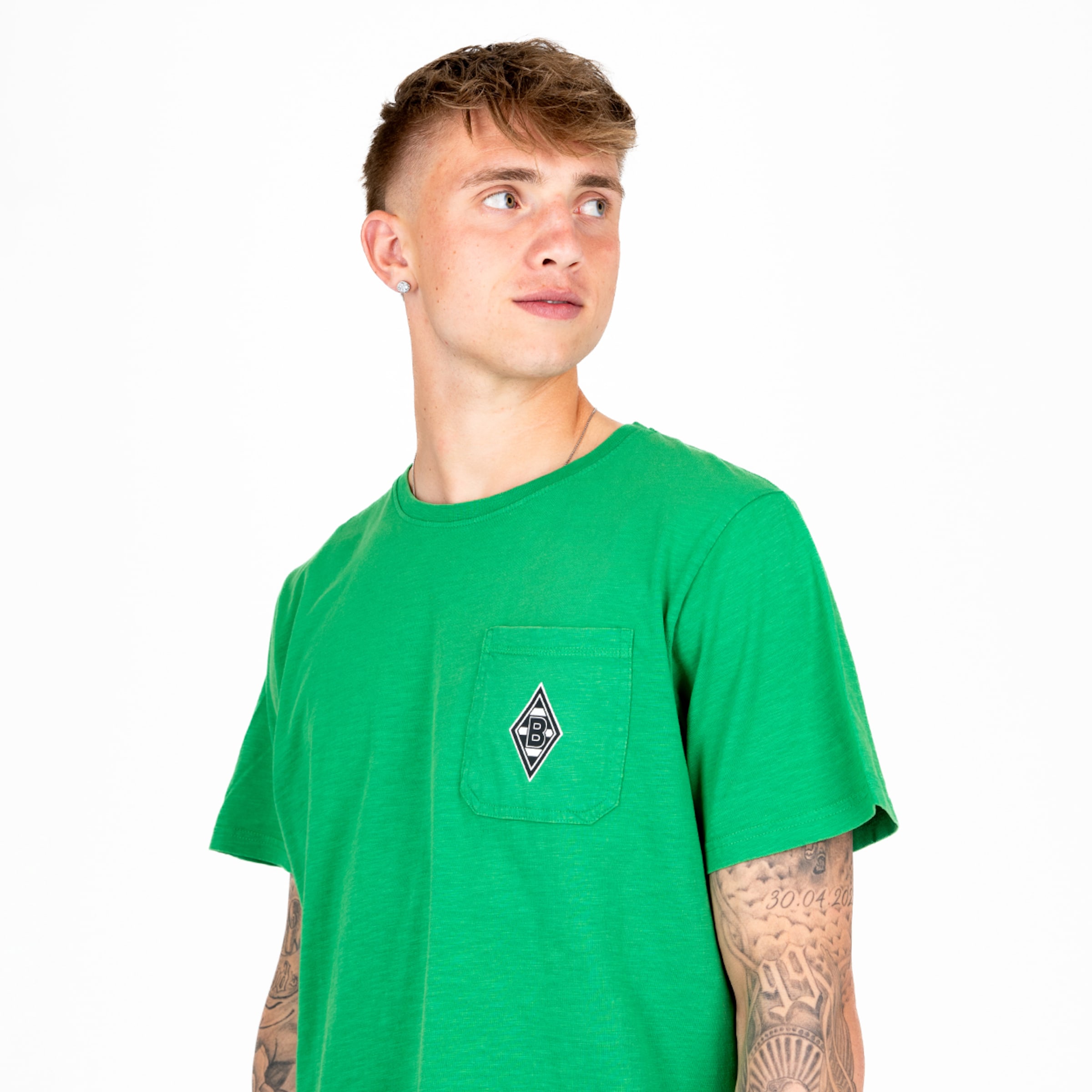 Mann in grünem T-Shirt mit bleibendem Logo auf der Brust schaut nach oben.