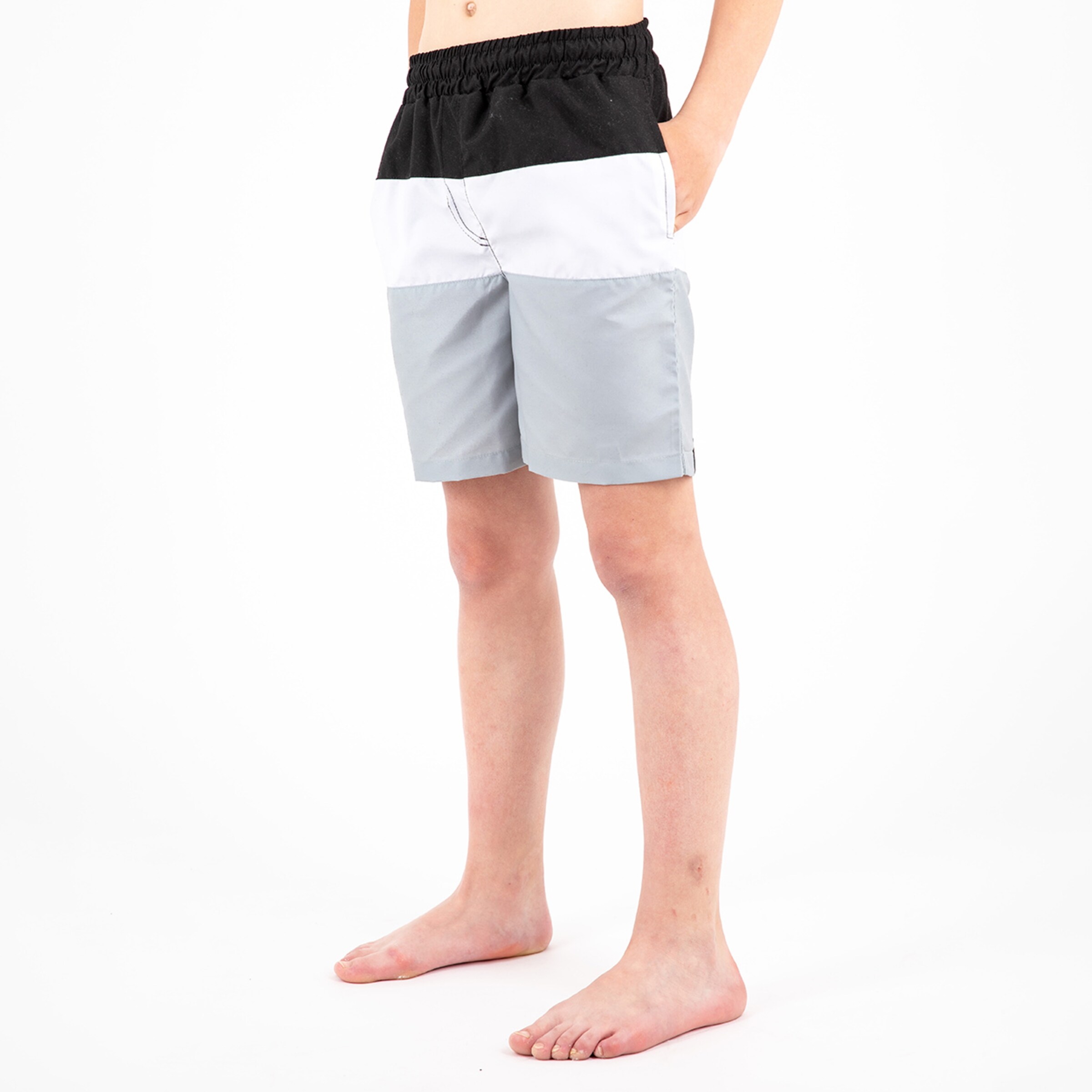 Junge in bunten Badeshorts mit elastischem Bund steht barfuß.