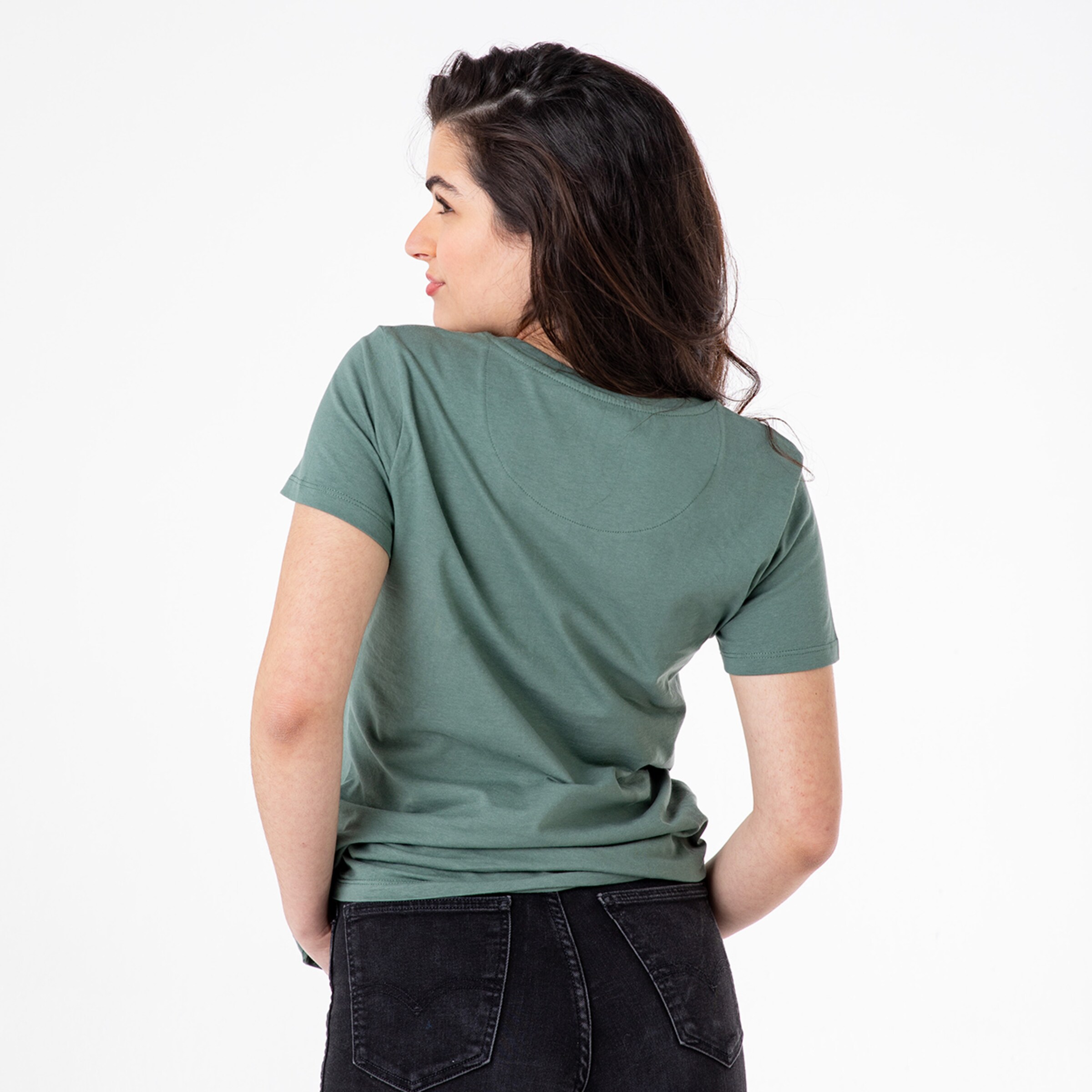 Woman wearing a green t-shirt viewed from the back. She is wearing black jeans.