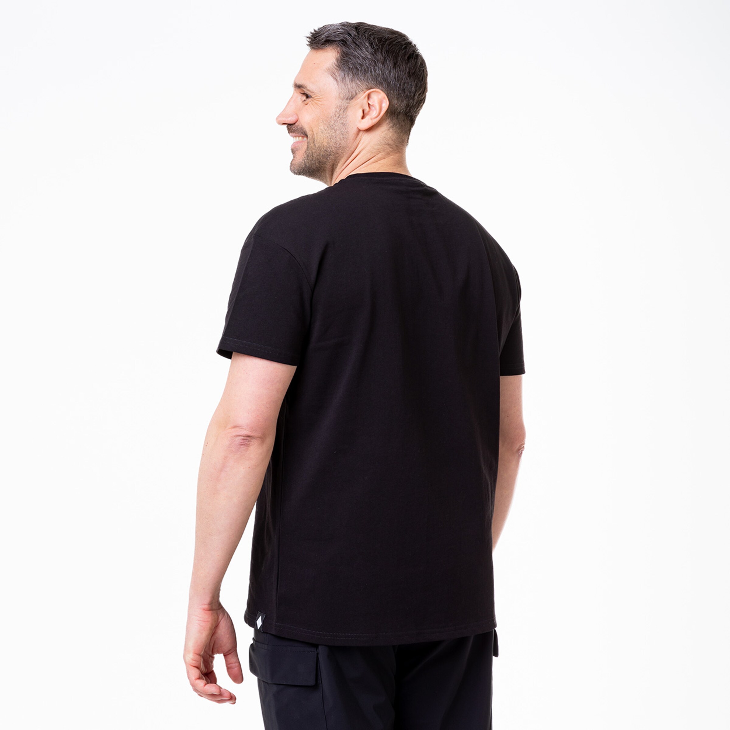 Mann in schwarzem T-Shirt von hinten fotografiert mit lächelndem Gesicht.