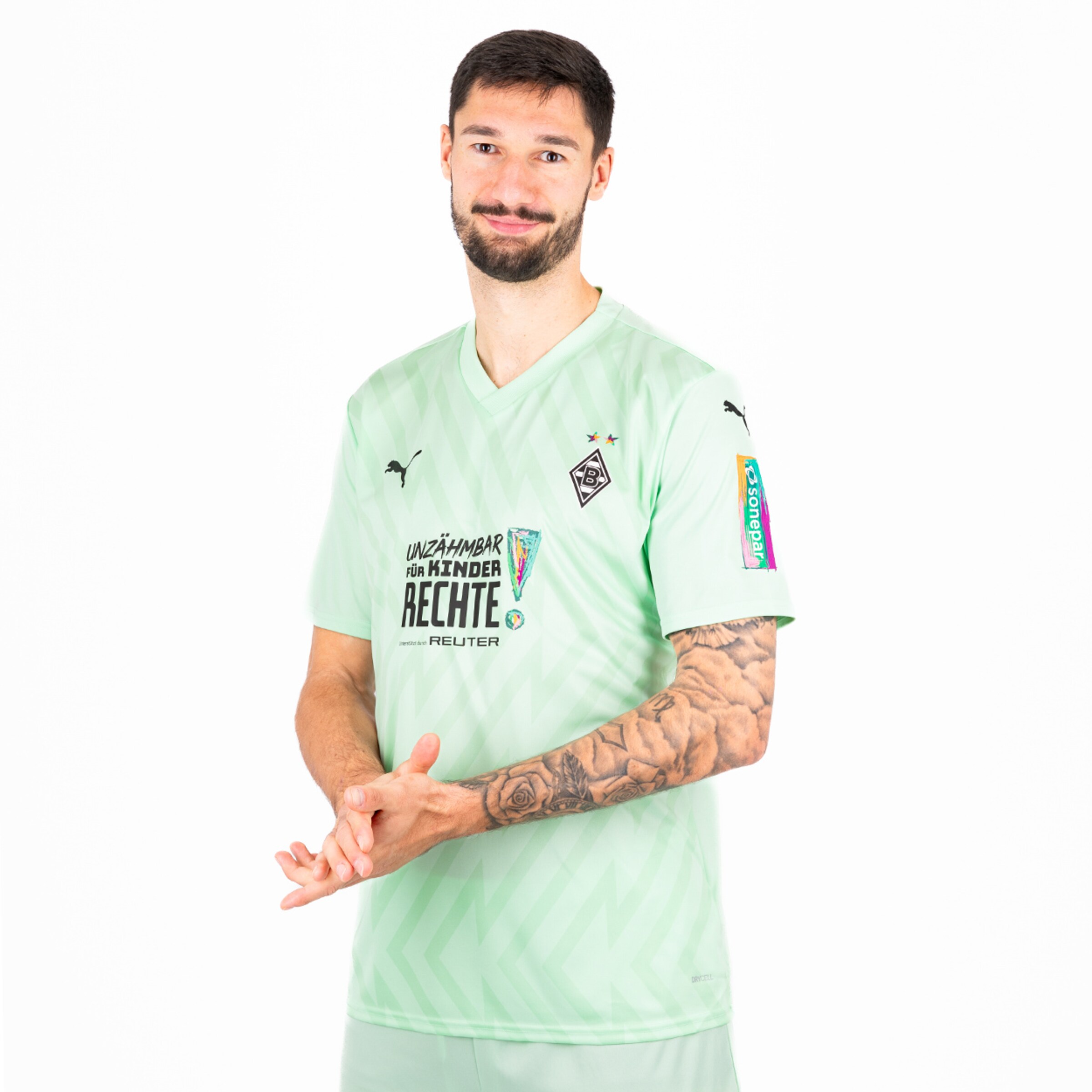 Fußballspieler in mintgrünem Trikot mit Tattoos auf dem rechten Arm.