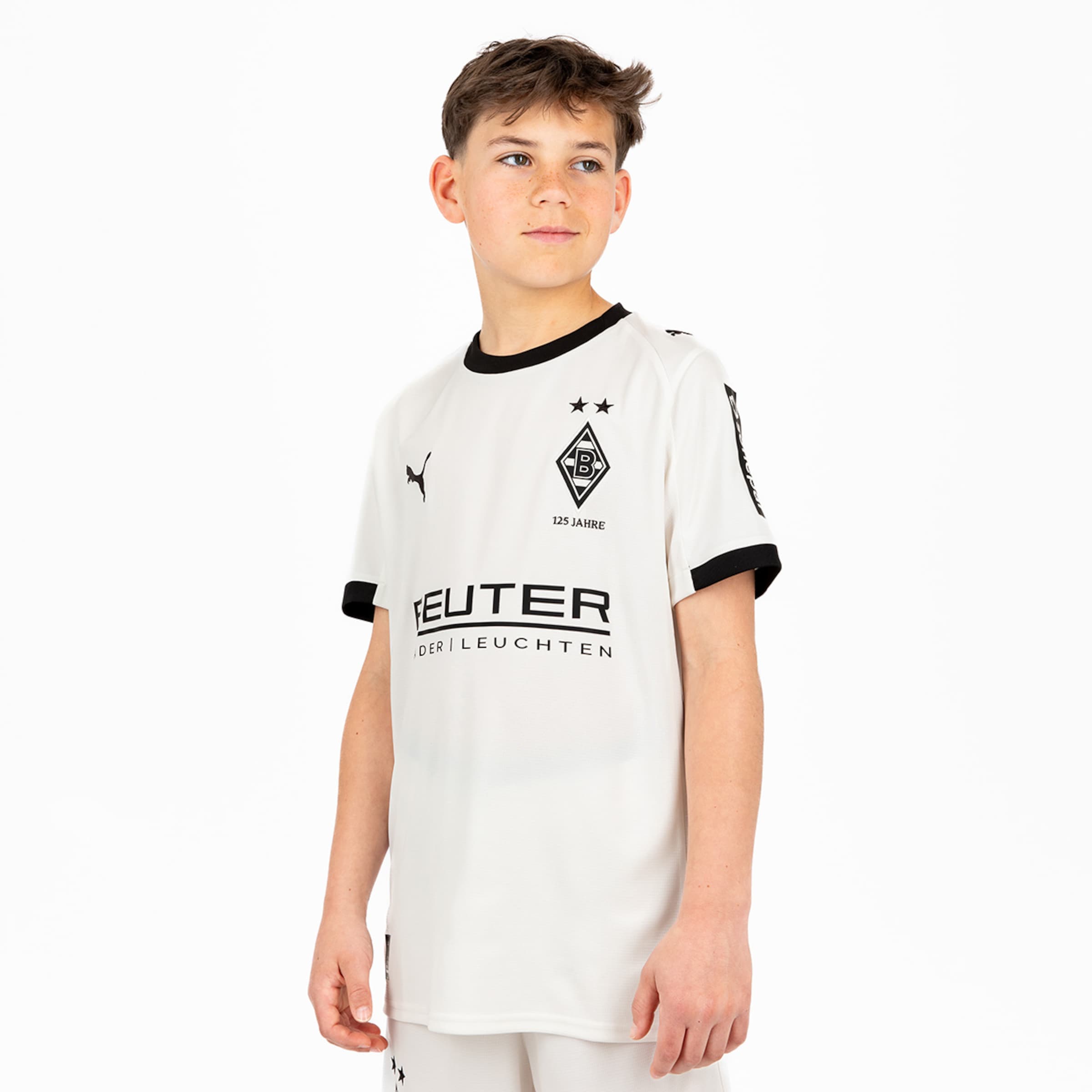 Ein Junge trägt das weiße Trikot von Borussia Mönchengladbach mit schwarzem Kragen und Aufdruck.