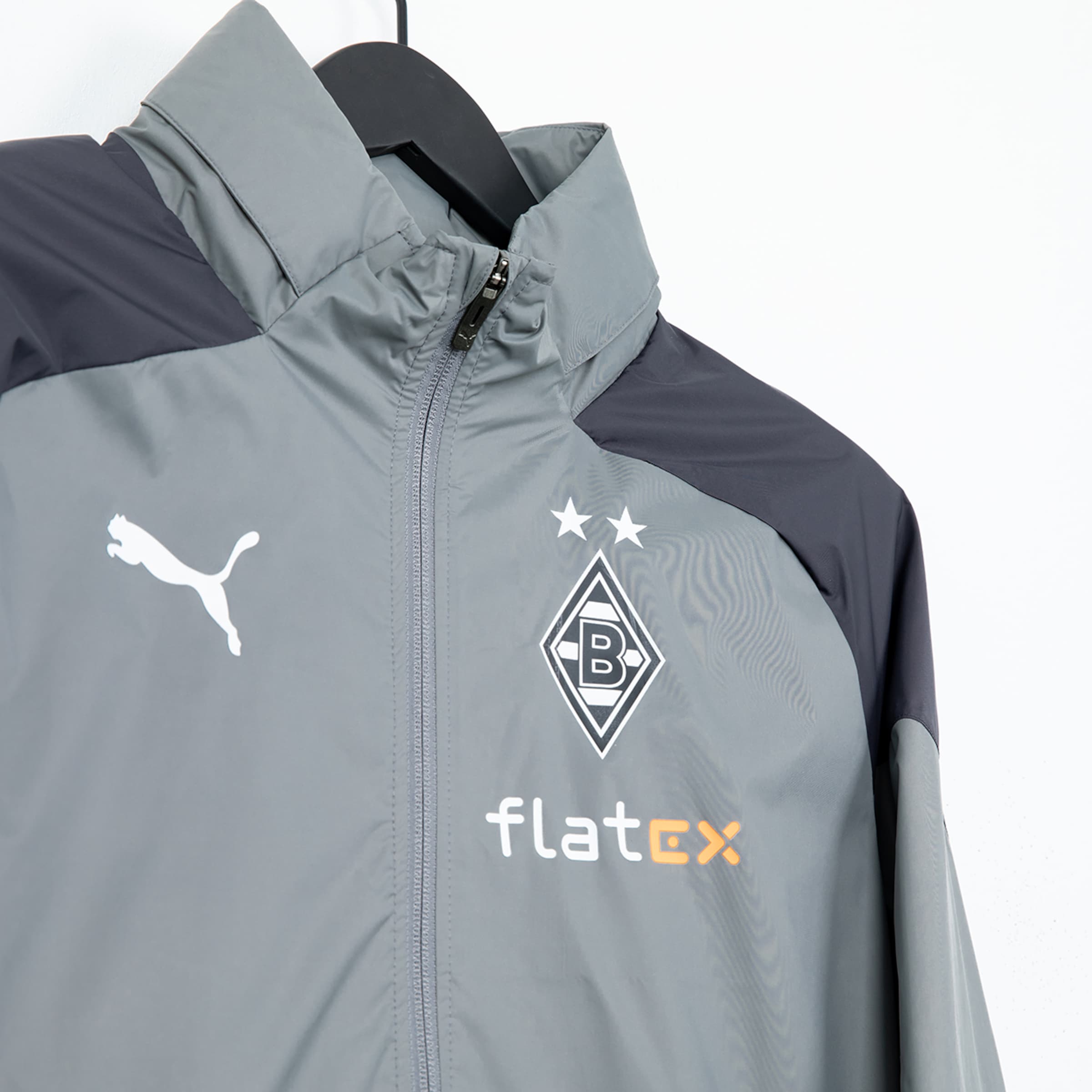 Grau-weiße Jacke von Puma mit Borussia Mönchengladbach-Logo und flatex-Schriftzug.
