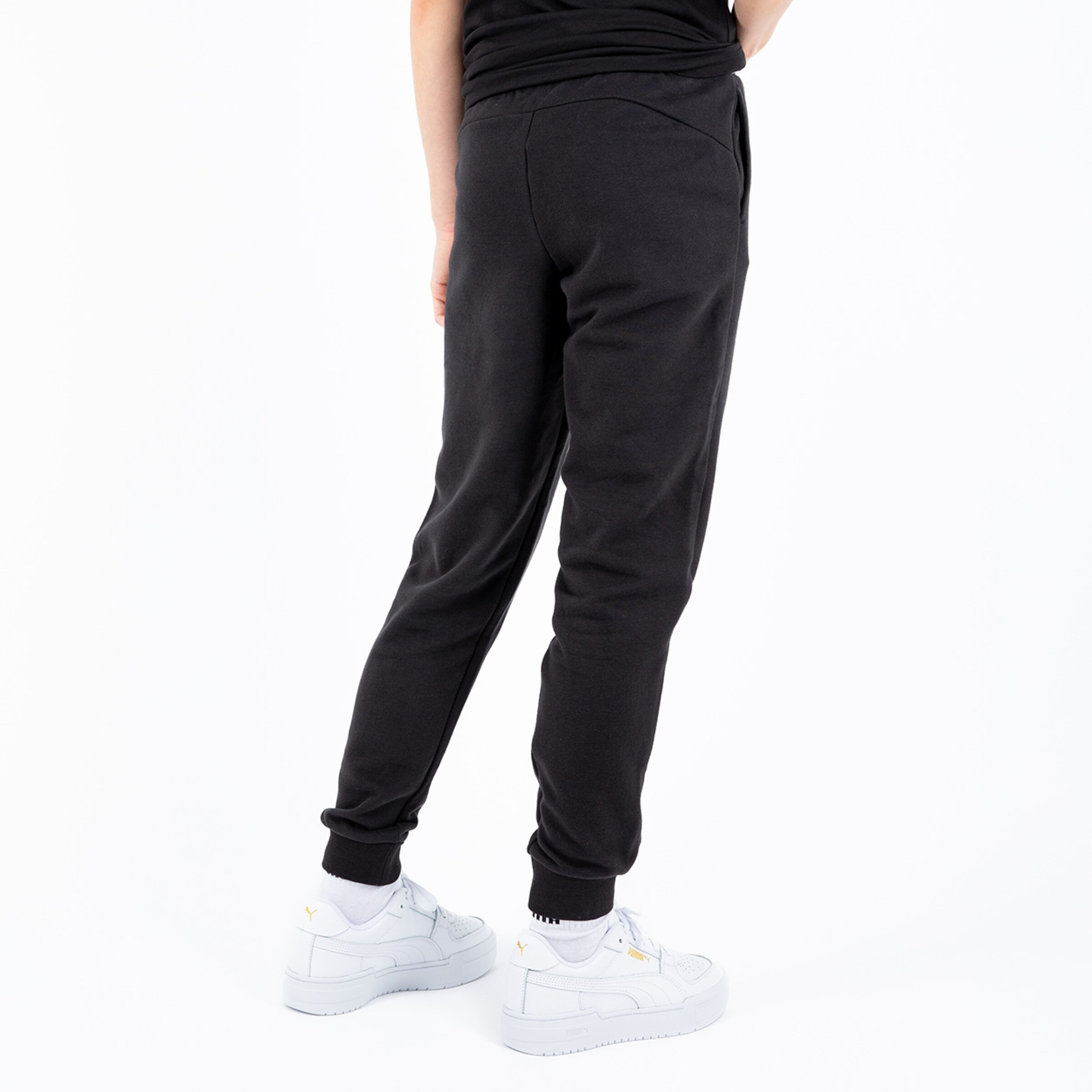 Black jogger pants with elastic waistband and side pockets worn by a person in sports shoes.