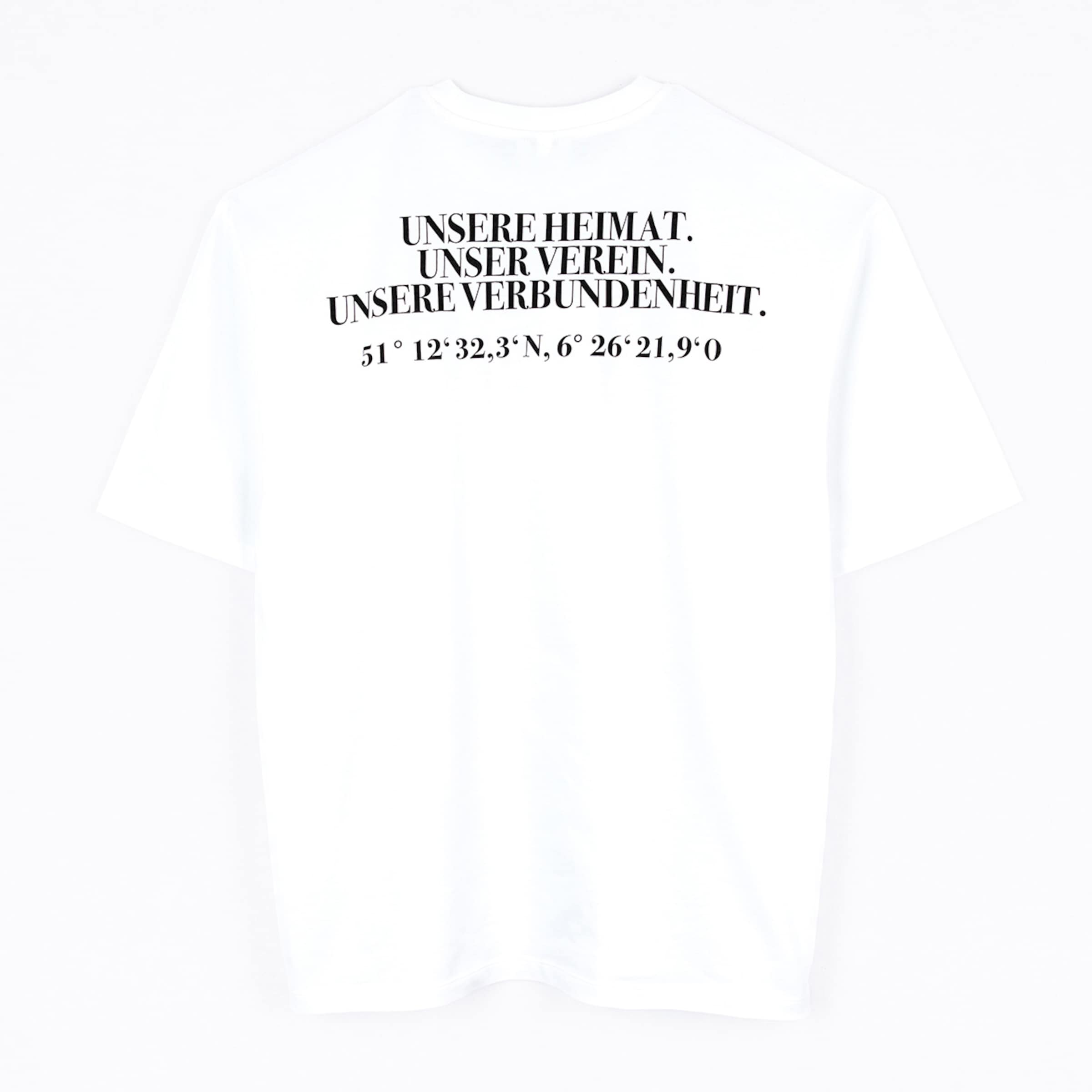 Rückseite eines weißen T-Shirts mit schwarzem Text: „UNSERE HEIMAT. UNSER VEREIN. UNSERE VERBUNDENHEIT.“ und geografischen Koordinaten.