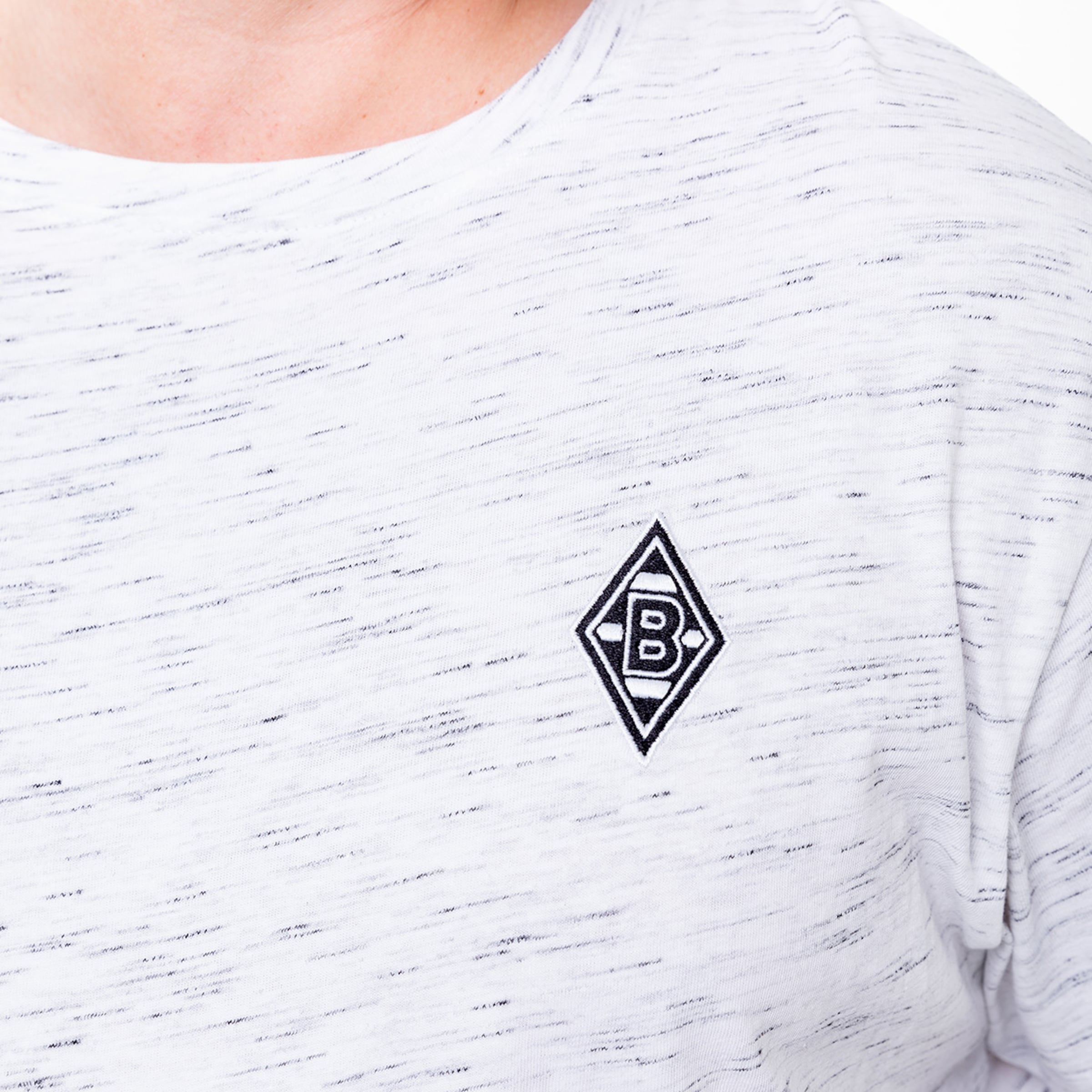 Ein graues T-Shirt mit einem gestickten Borussia Mönchengladbach-Logo auf der linken Brustseite.