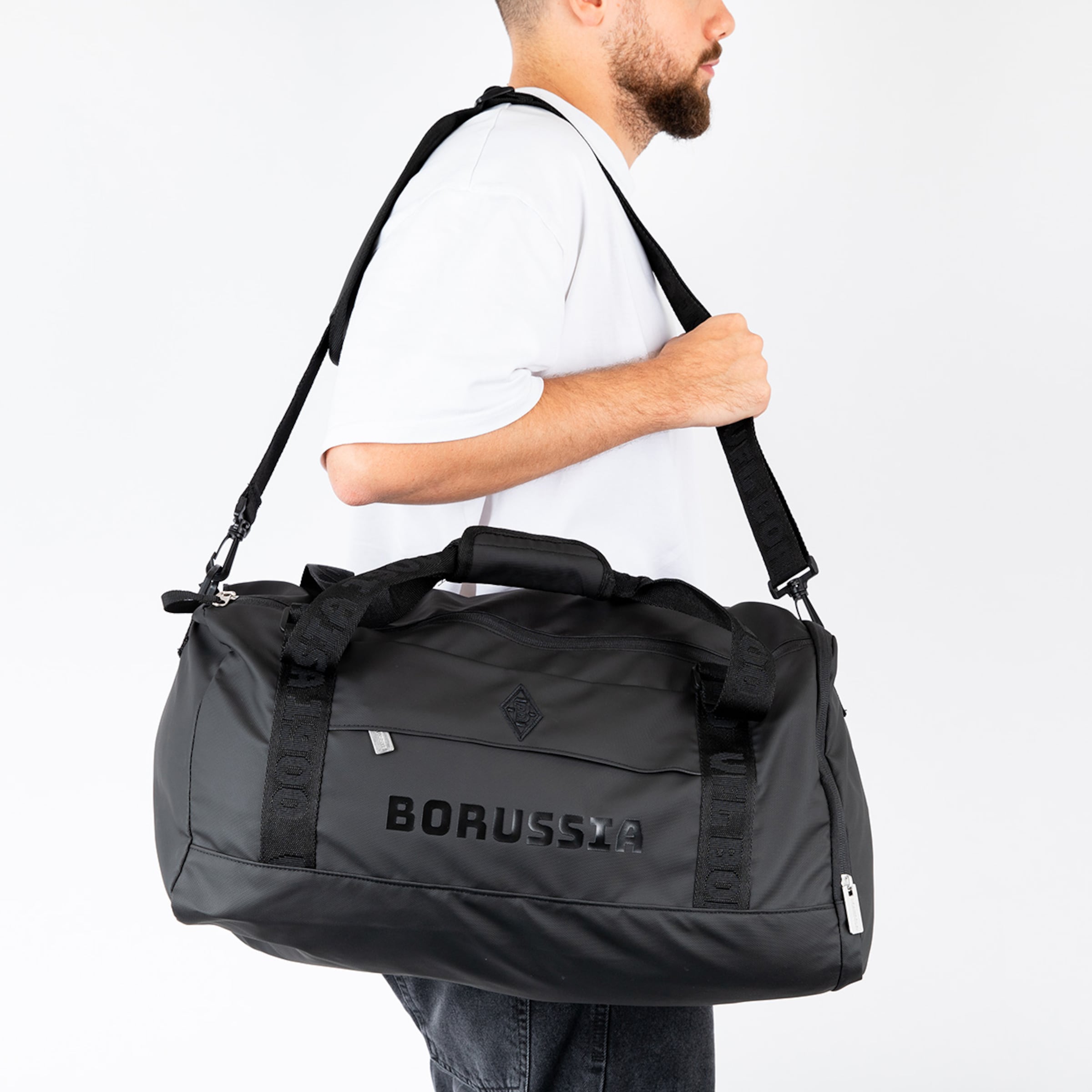 Schwarze Sporttasche mit dem Schriftzug BORUSSIA auf der Seite getragen von einem Mann.