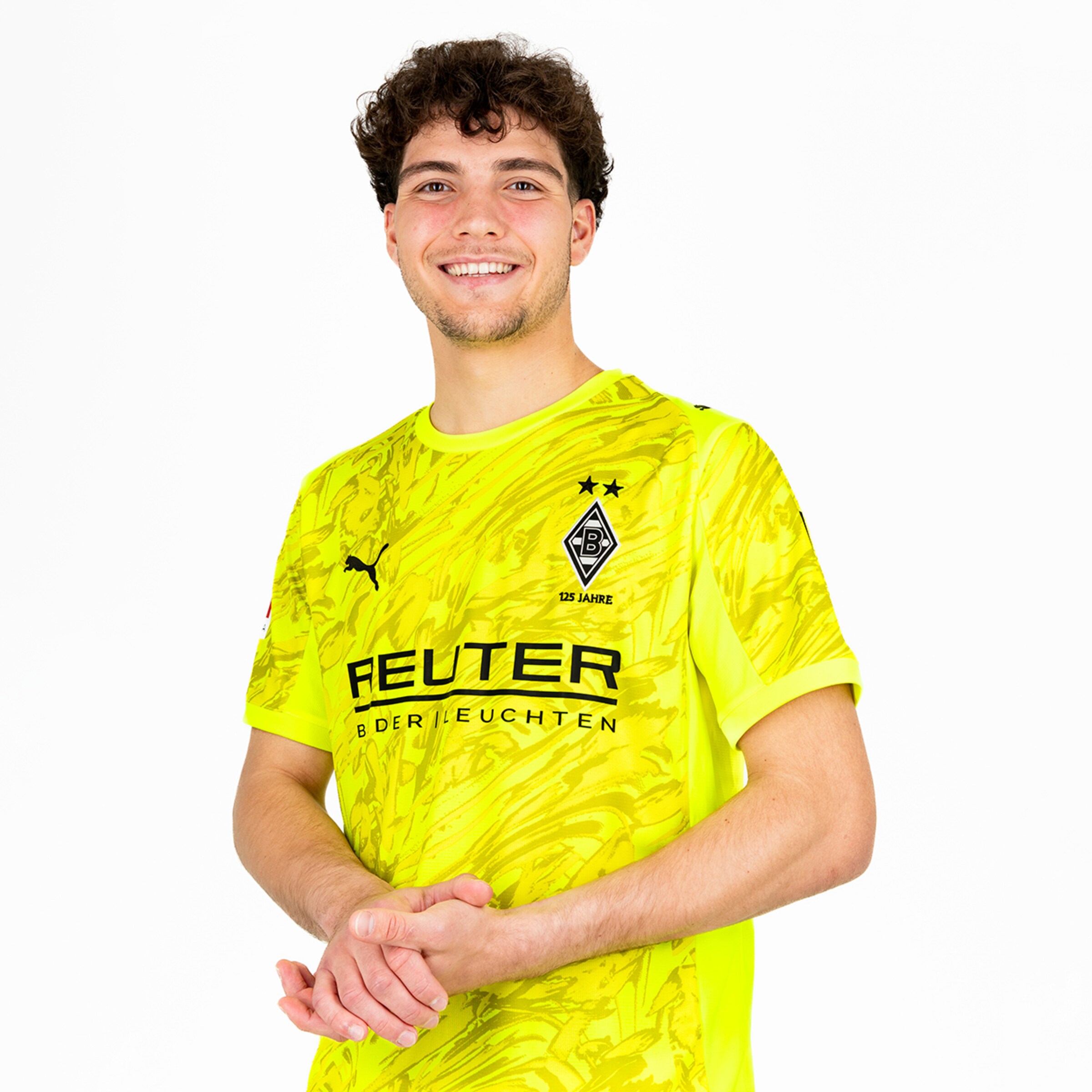 Goalkeeper in yellow jersey with a smiling expression posing against a neutral background.