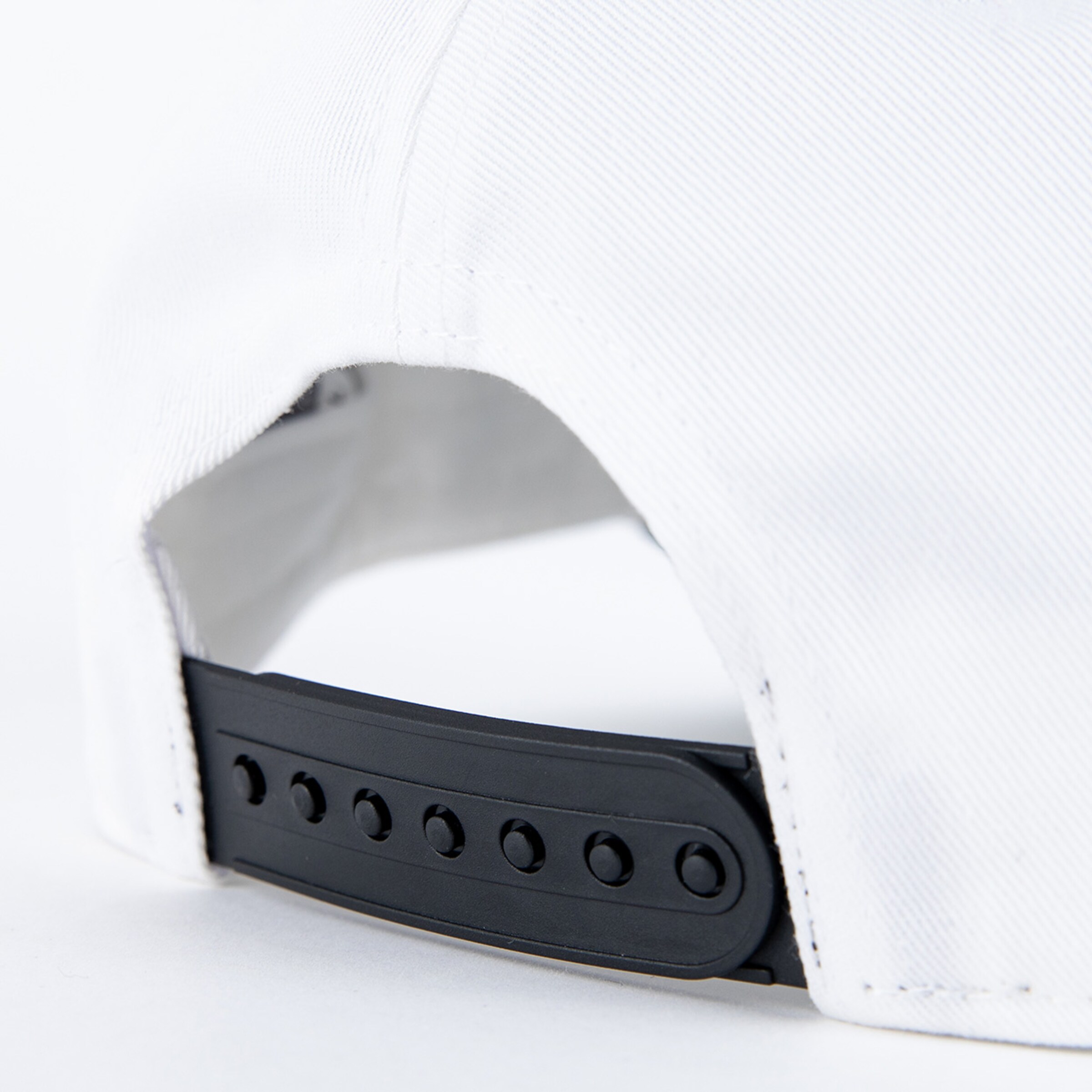 Close-up of a white cap featuring a black snapback closure.