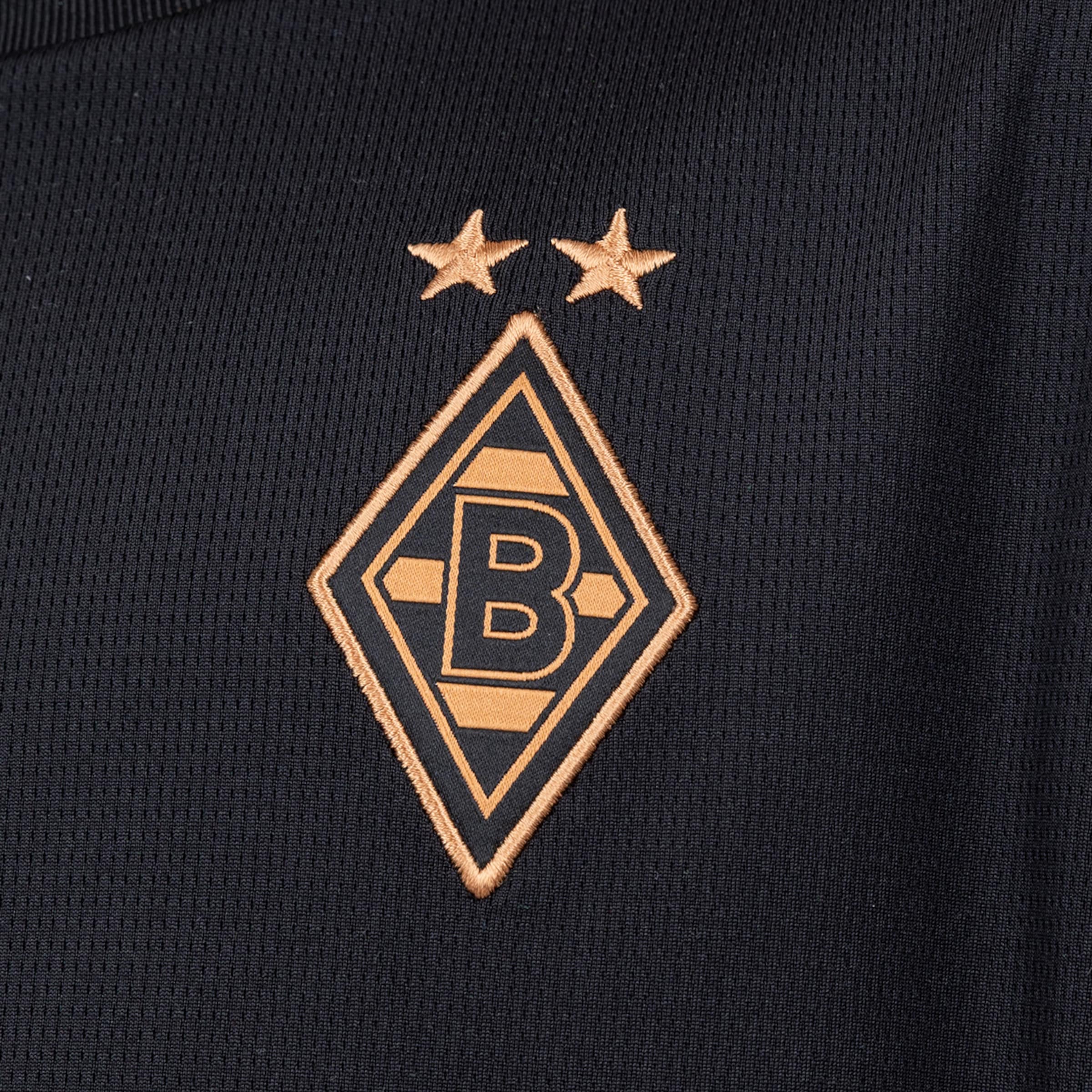 Gesticktes Logo von Borussia Mönchengladbach in Bronze auf schwarzem Stoff. Eine Raute mit dem Buchstaben B und zwei Sternen darüber.