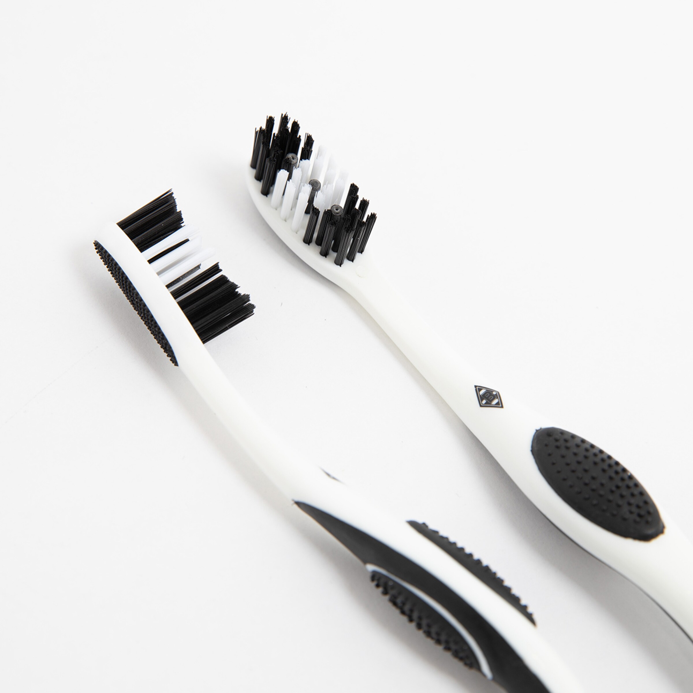 Two black and white toothbrushes on a white background with mixed black and white bristles.