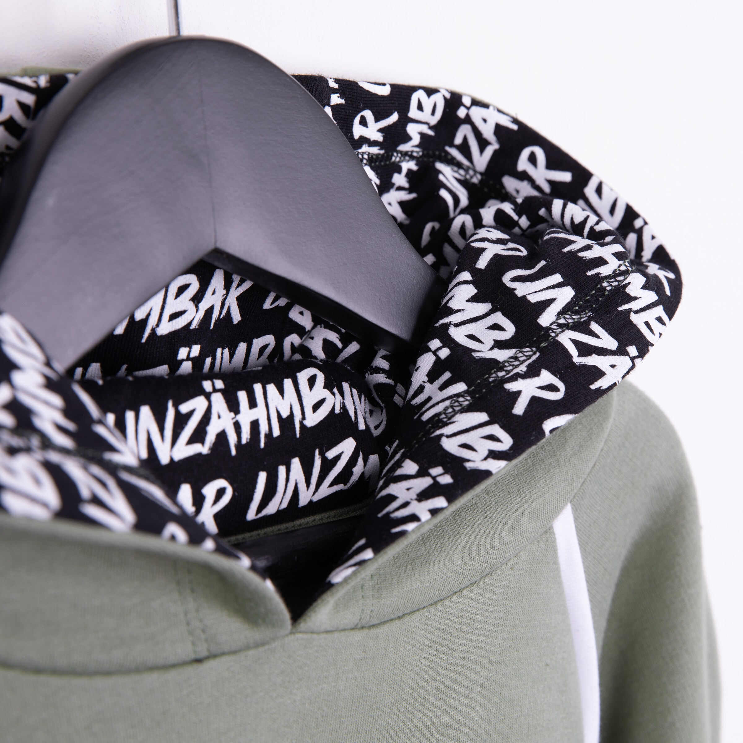 Grüne Kapuzenjacke mit einem schwarz-weißen aufgedruckten Innenfutter.