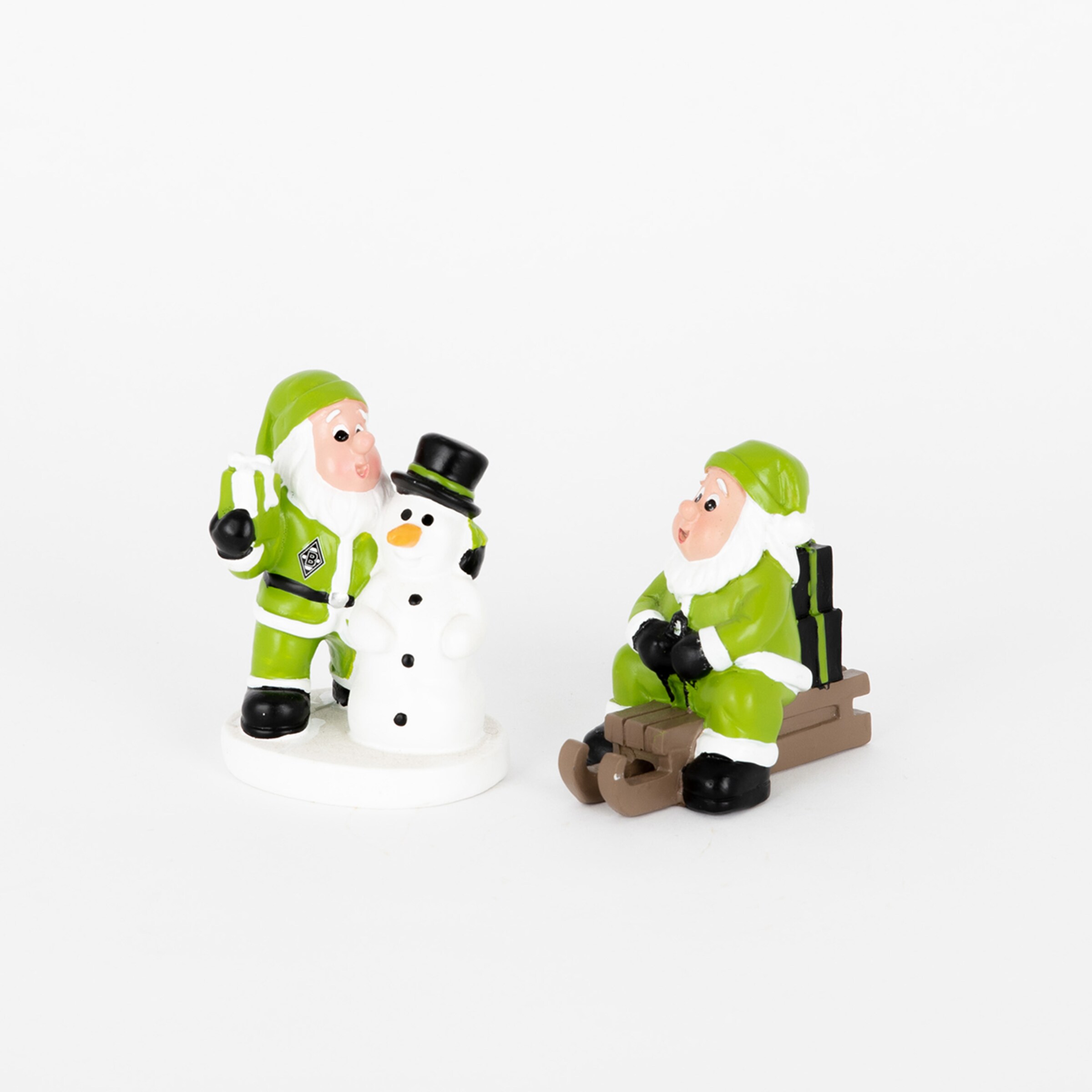 Zwei Weihnachtsmänner in grünen Anzügen einer mit einem Schneemann und der andere sitzt auf einem Schlitten.