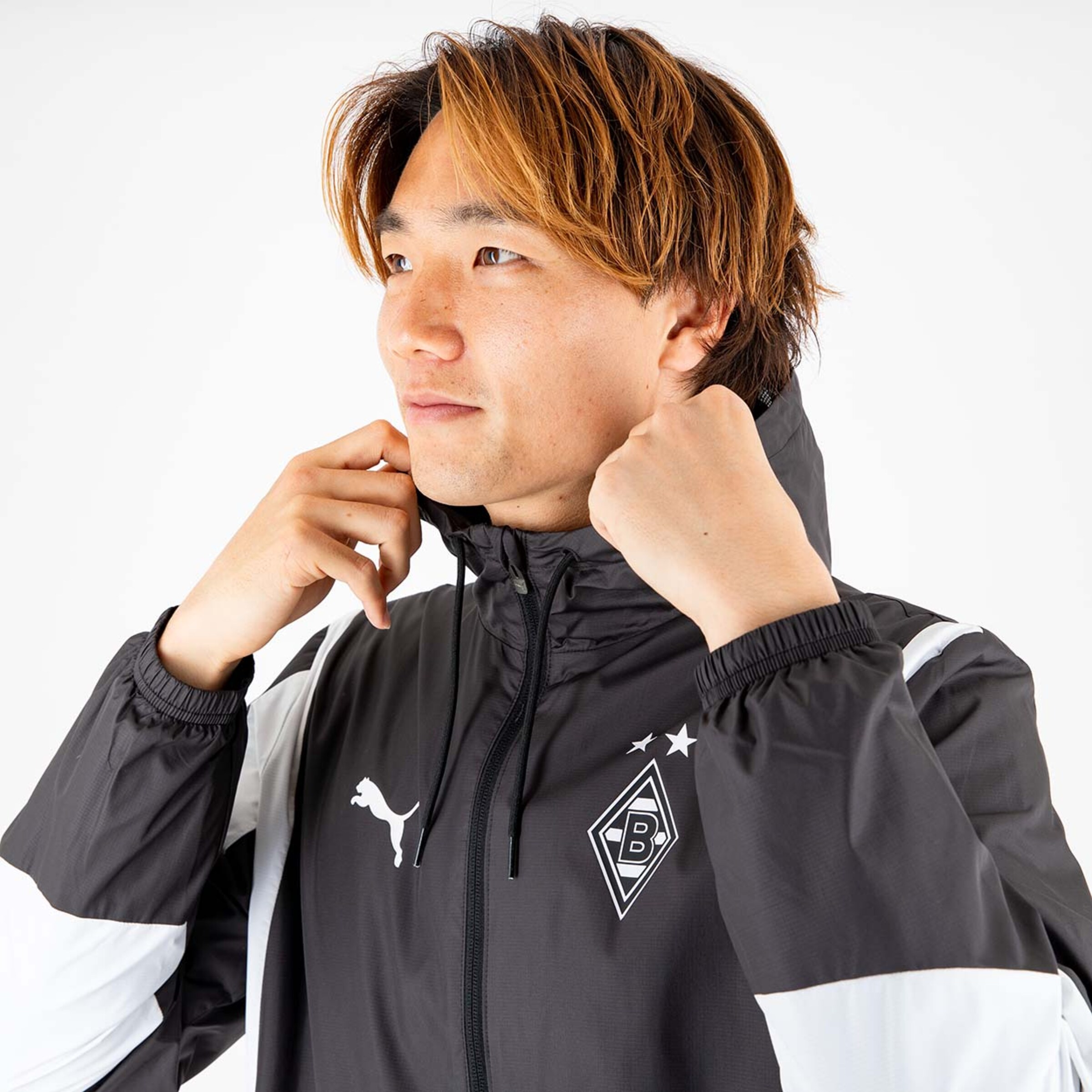 Mann trägt eine schwarze Jacke mit weißem Puma-Logo und Borussia Mönchengladbach-Emblem.