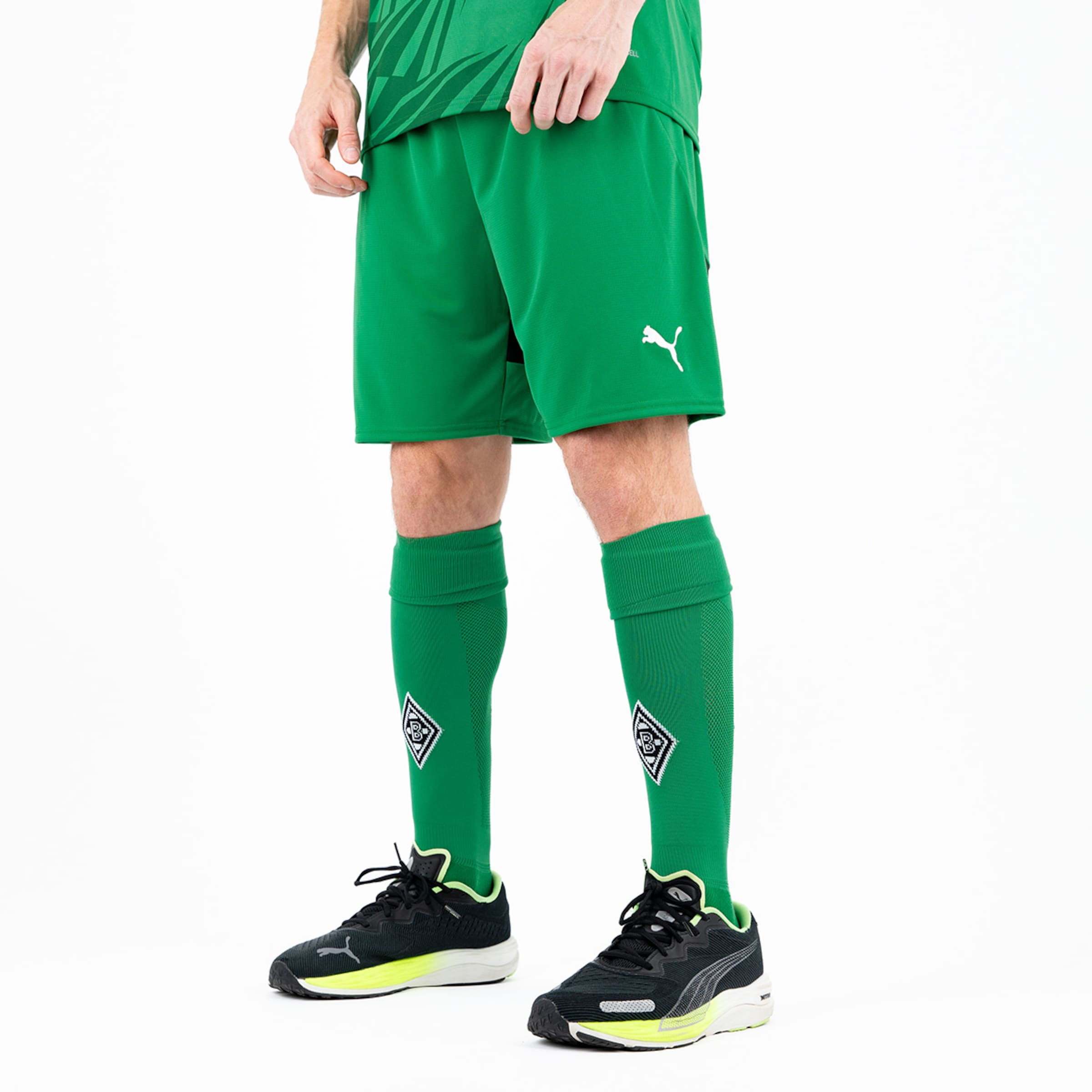 Ein Spieler trägt ein grünes Fußballtrikot und Shorts von Puma mit schwarzen Fußballschuhen und grünen Strümpfen.
