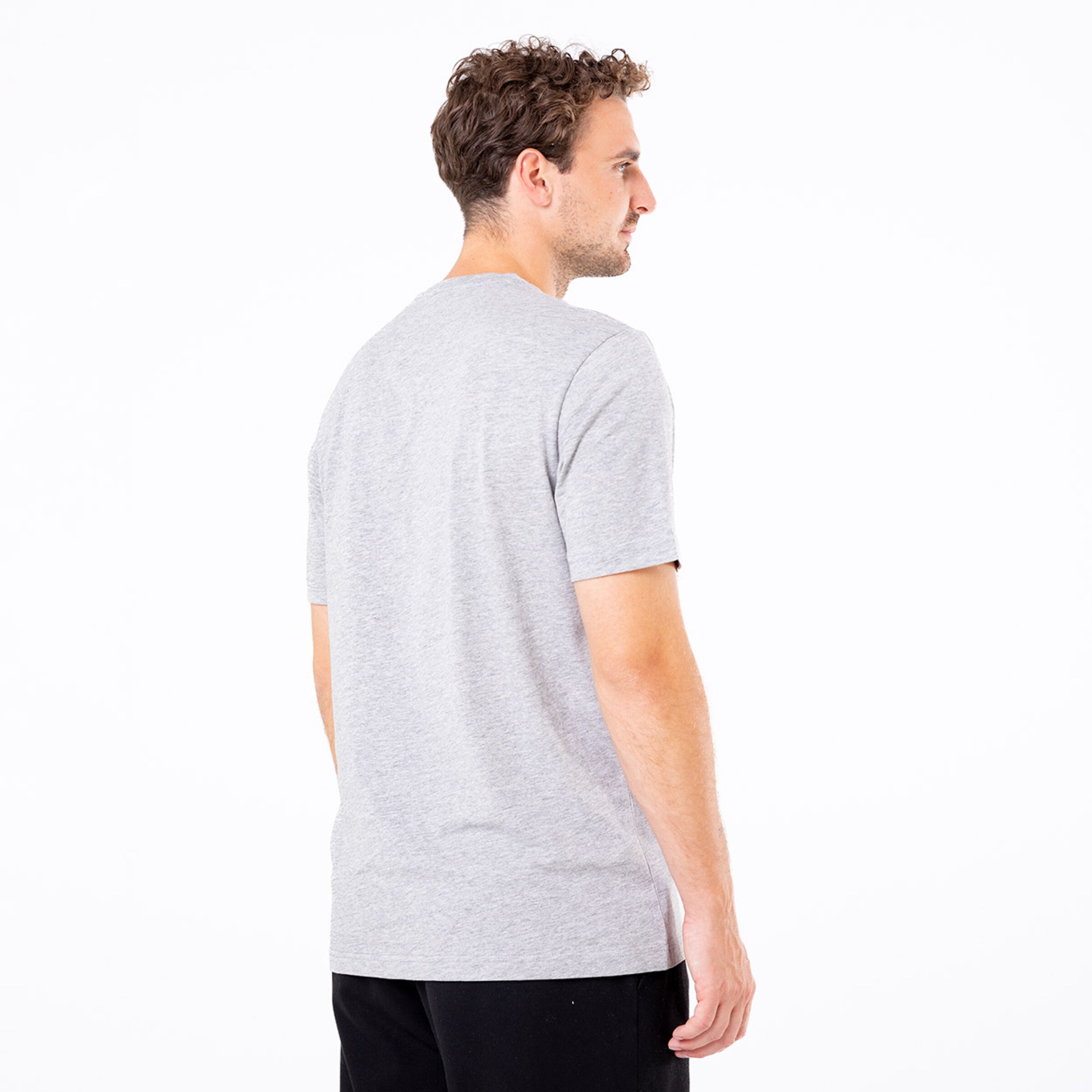 Mann mit lockigen Haaren trägt ein graues T-Shirt von hinten.