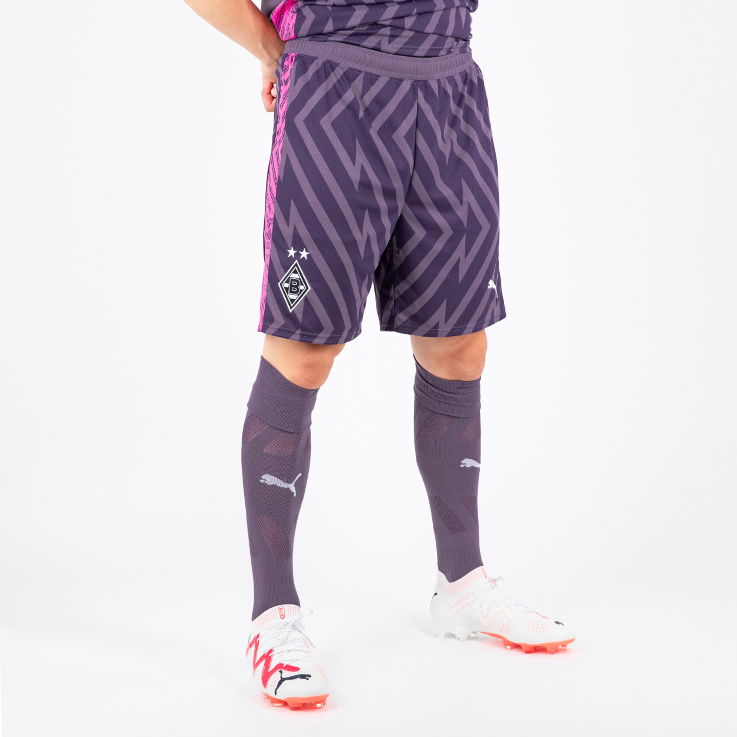 Spieler trägt lila Fußballshorts und Socken von Puma gestreift mit Borussia Mönchengladbach-Logo.