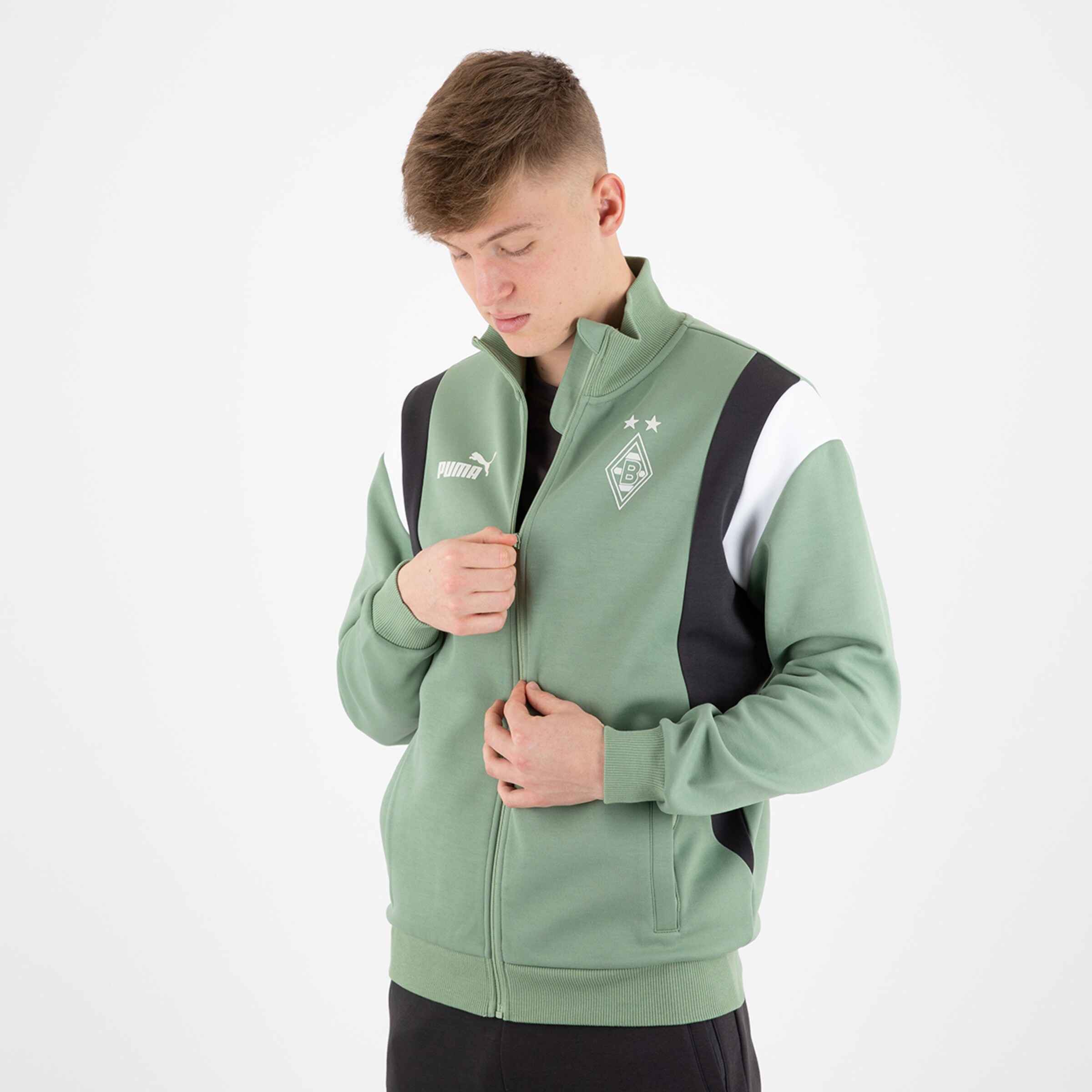 Junger Mann trägt eine grüne Borussia Mönchengladbach Jacke mit Logo.