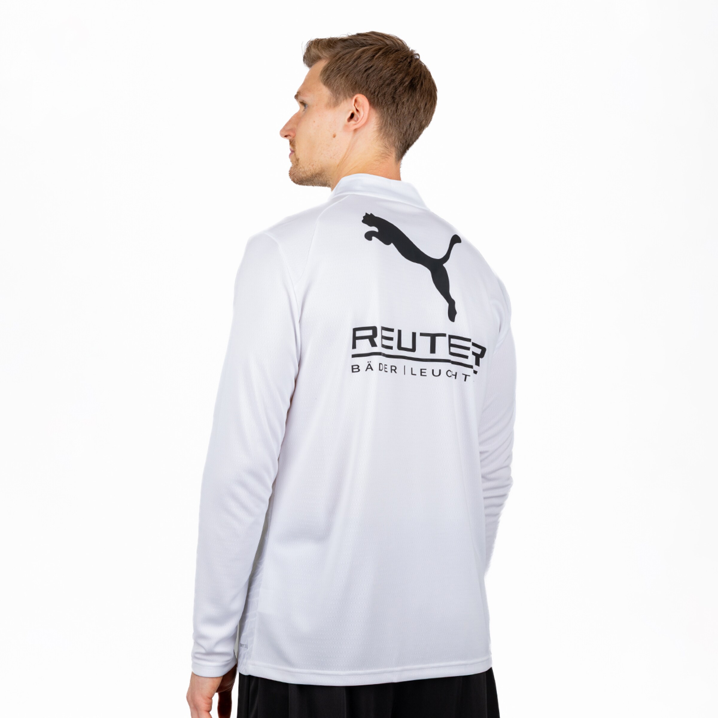Ein Mann von hinten, nach links blickend, trägt ein weißes Langarmshirt mit schwarzem Puma-Logo und dem Schriftzug 'REUTER BÄDER | LEUCHT' auf dem Rücken.