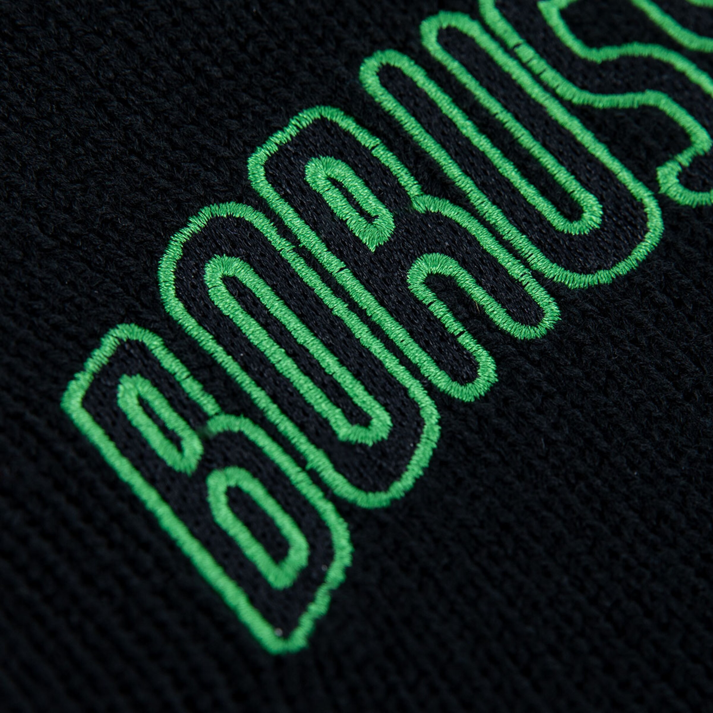 Detailaufnahme des Schriftzugs BORUSSIA auf einem schwarzen Textil mit grüner Stickerei.