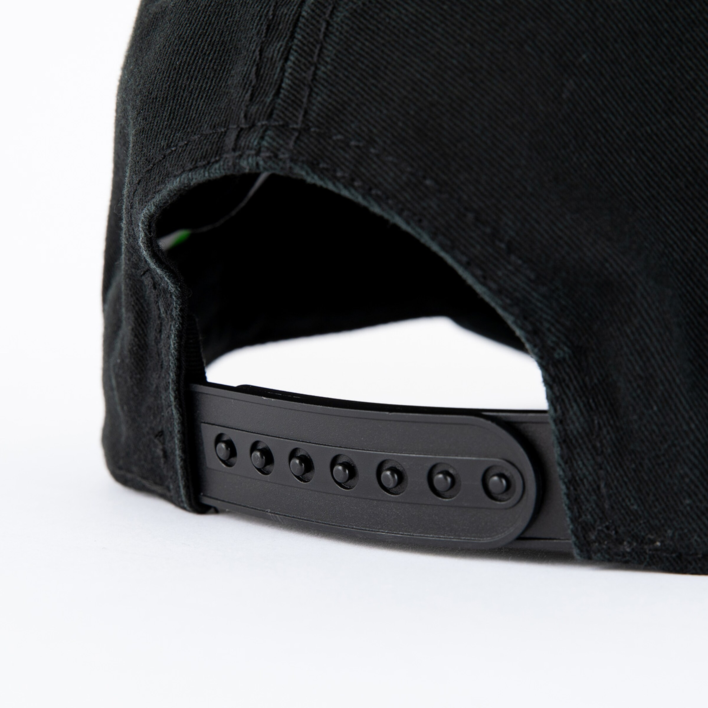 Close-up of the strap of a black baseball cap.