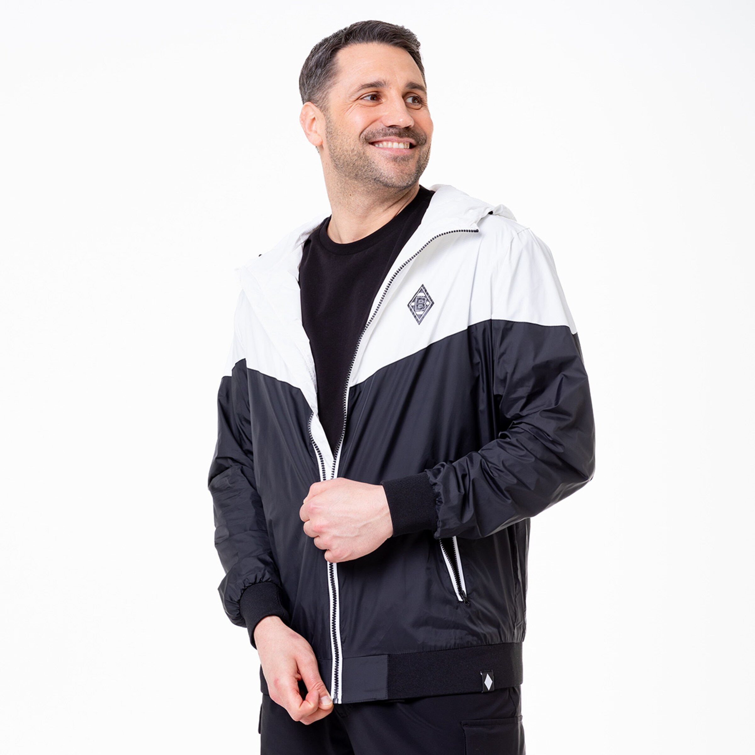Man wearing a black and white hooded jacket featuring the Borussia Mönchengladbach logo.