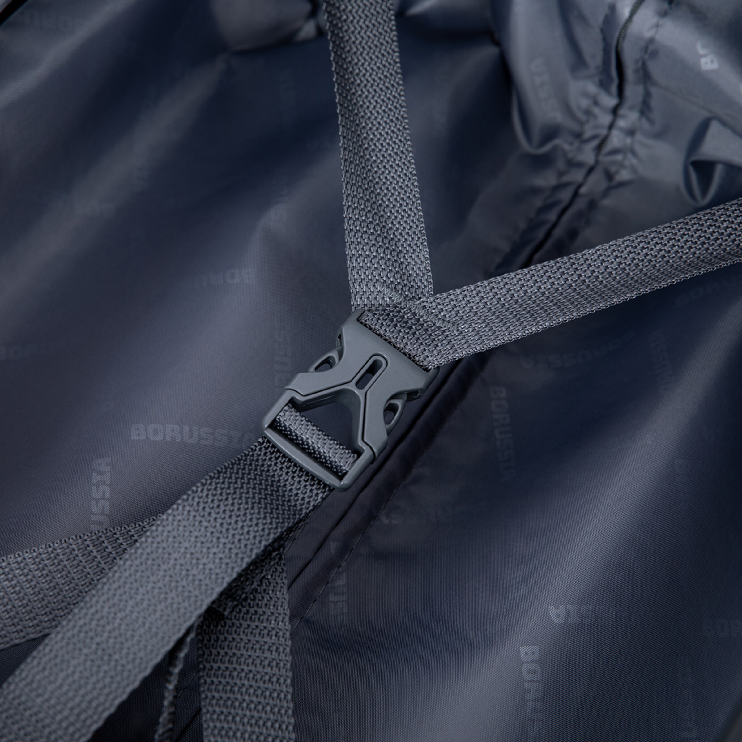 Close-up of a strap on a black backpack featuring a plastic buckle with BORUSSIA text.