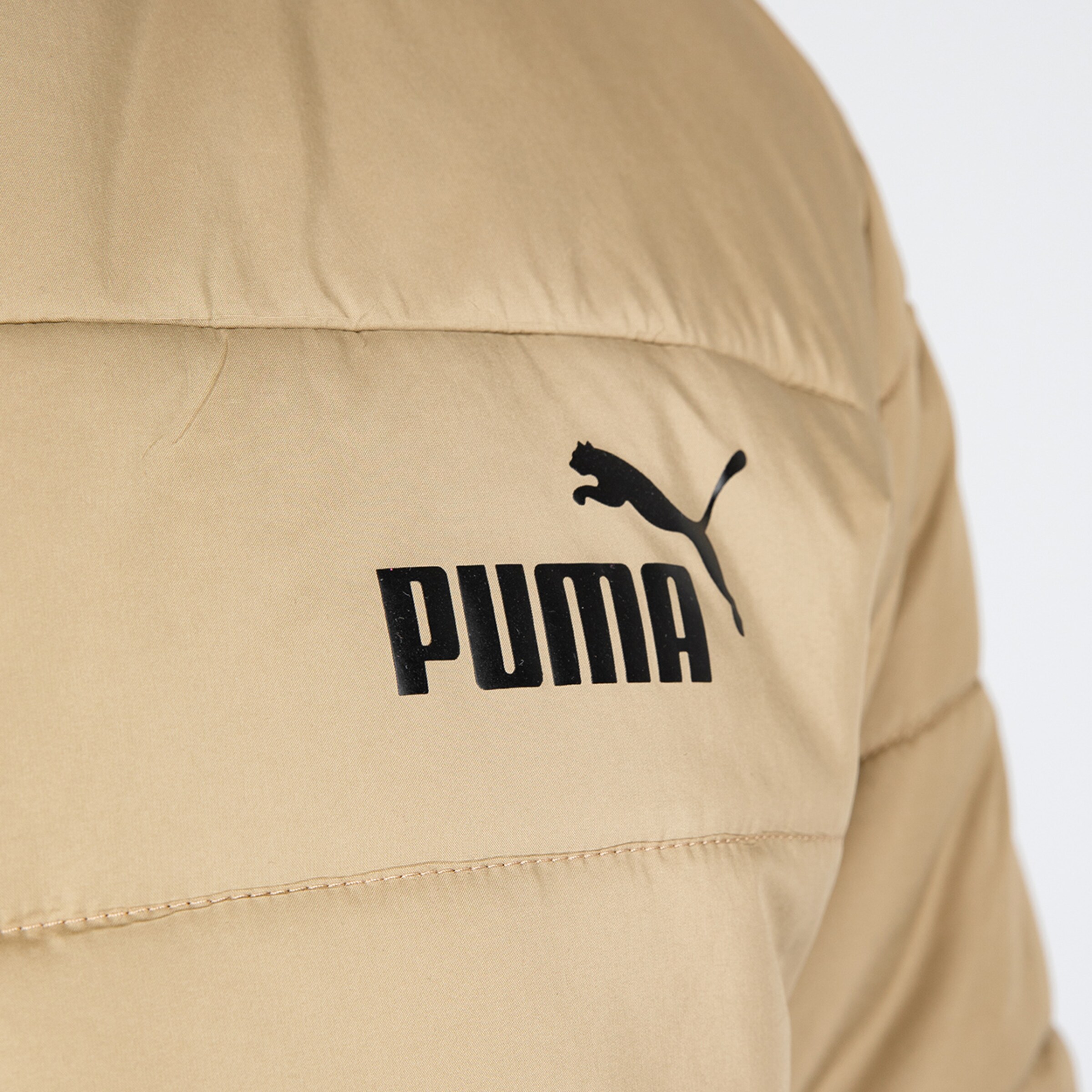 Nahaufnahme eines beige Puma-Jackets mit schwarzem Logo.