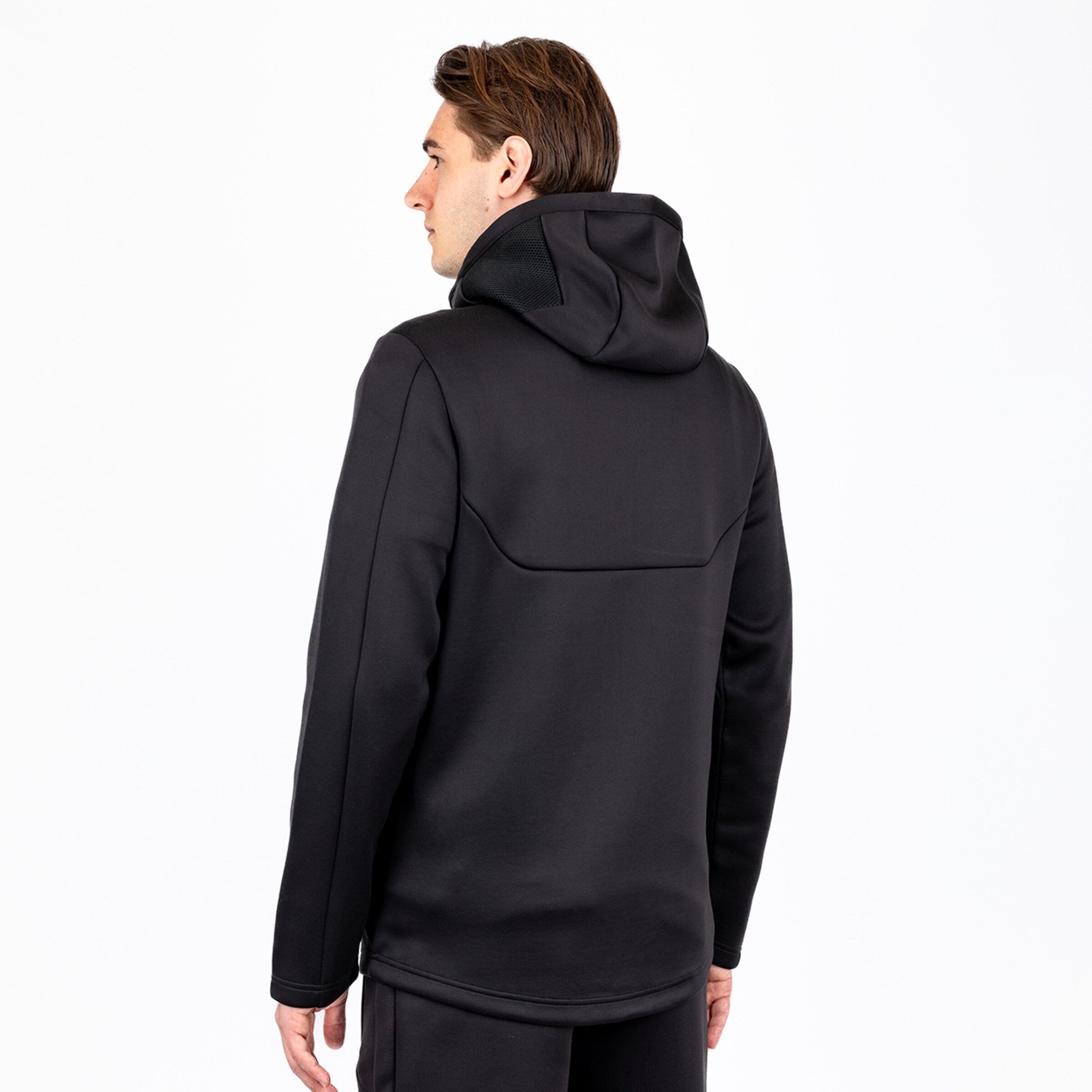 Mann von hinten in einer schwarzen Kapuzenjacke die eng am Körper anliegt.