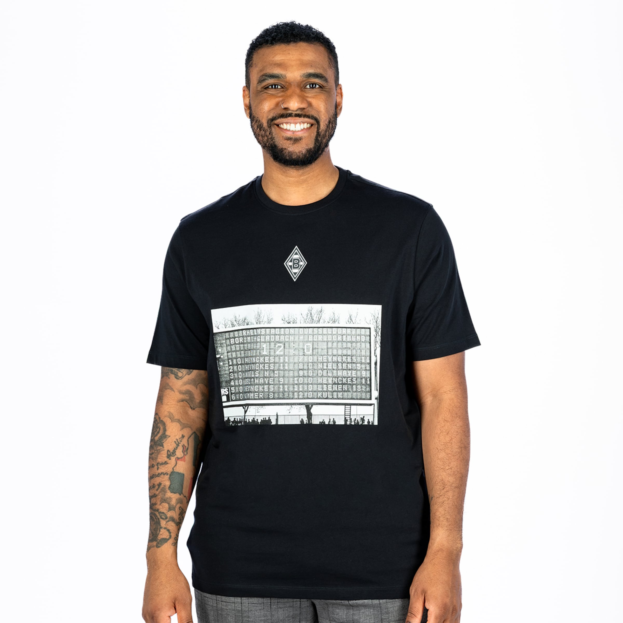 Smiling man in a black Borussia Mönchengladbach t-shirt with a print of the 12-0 scoreboard against Dortmund on a white background.