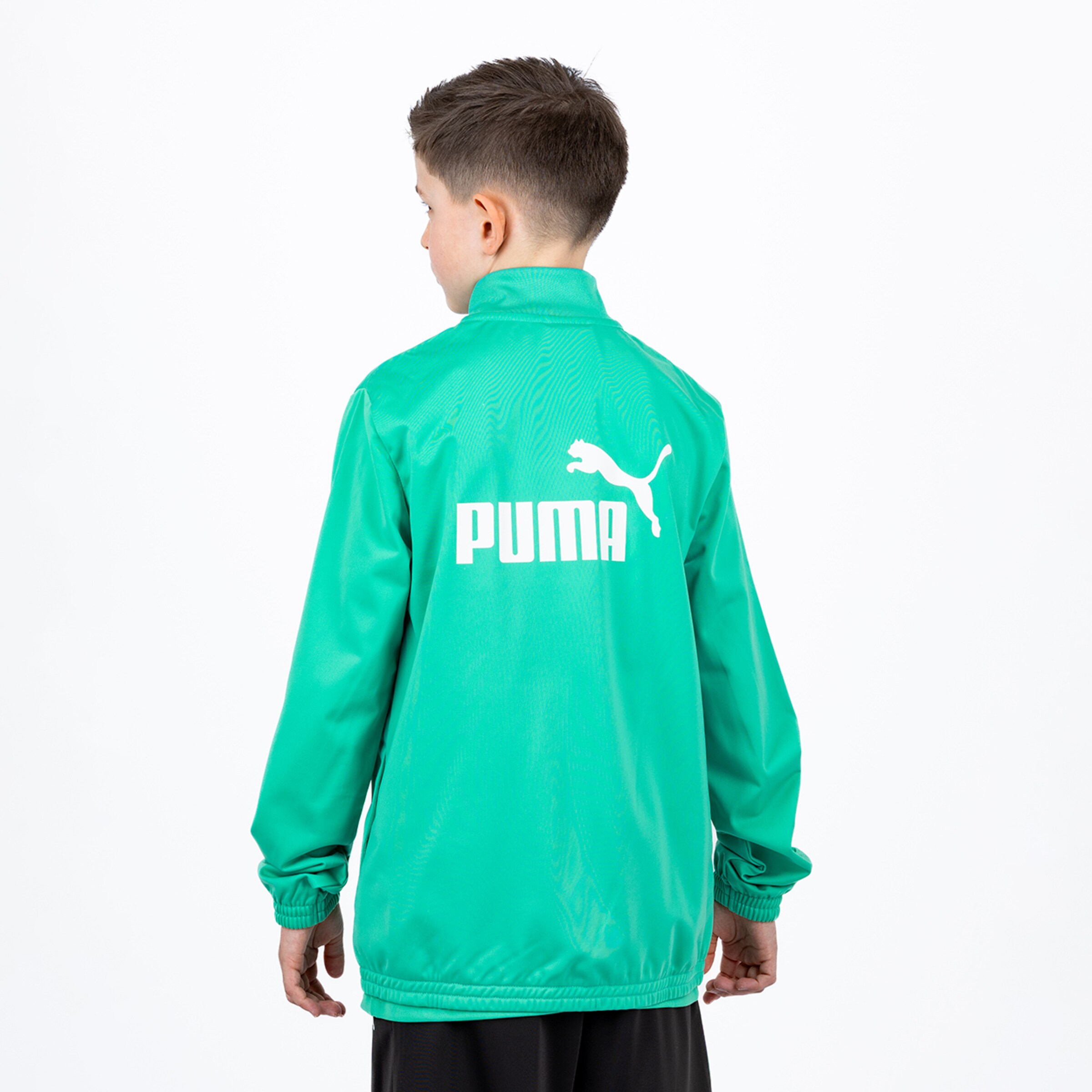 Back view of a boy wearing a green Puma sports jacket with a large white logo on the back.