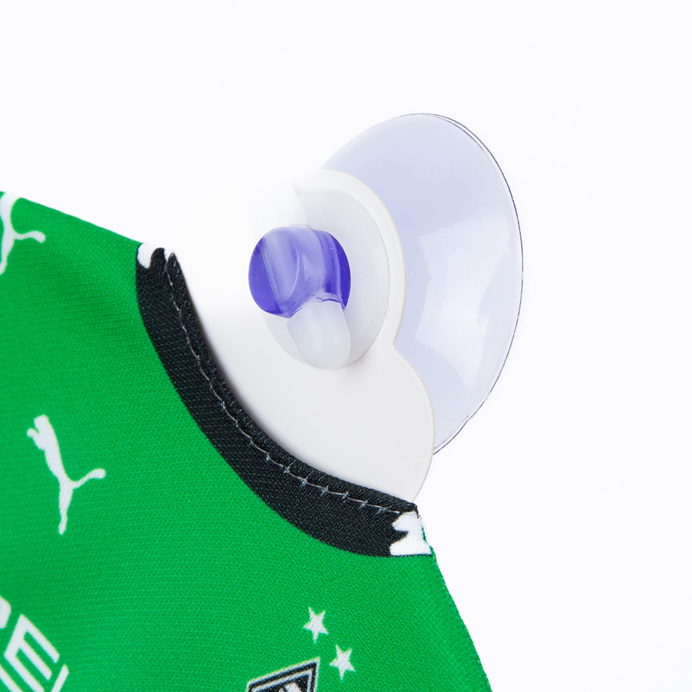 Puma-Anhänger in Form eines Saugnapfes am Kragen eines grünen T-Shirts.