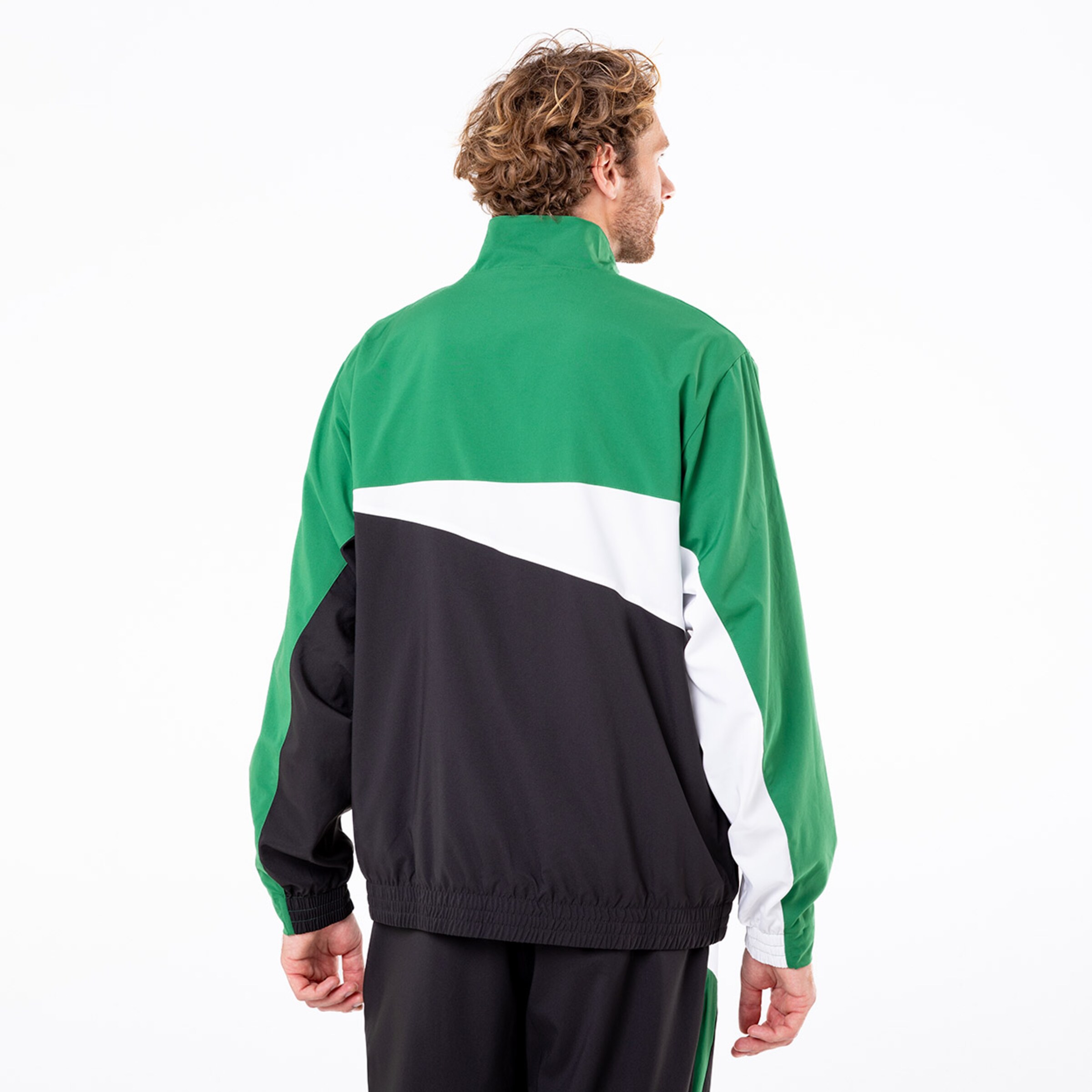 Mann in sportlicher Jacke mit grünem schwarzem und weißem Design von hinten gesehen.