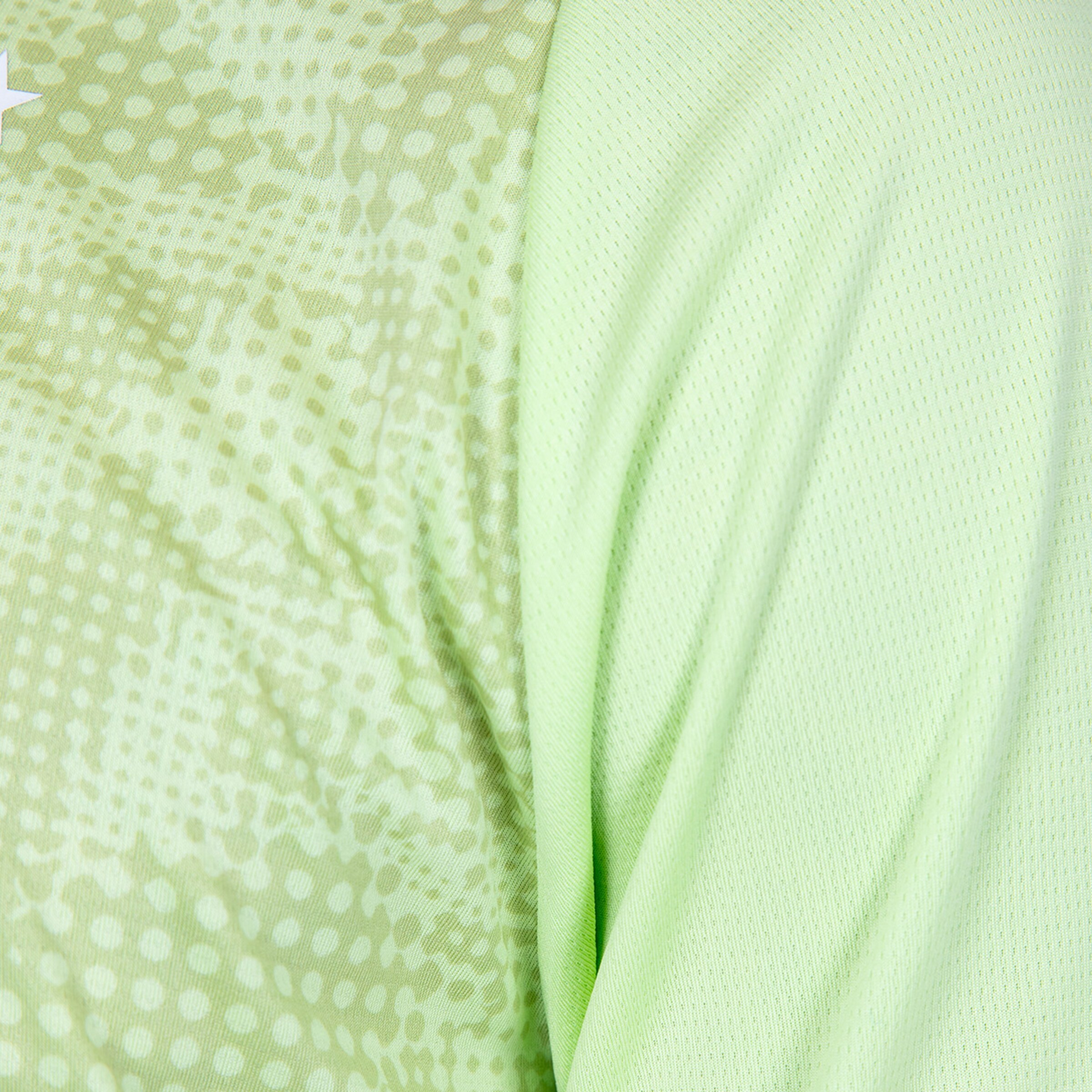 Detailansicht eines hellgrünen Trikots mit Punktmuster und Netzstoff.